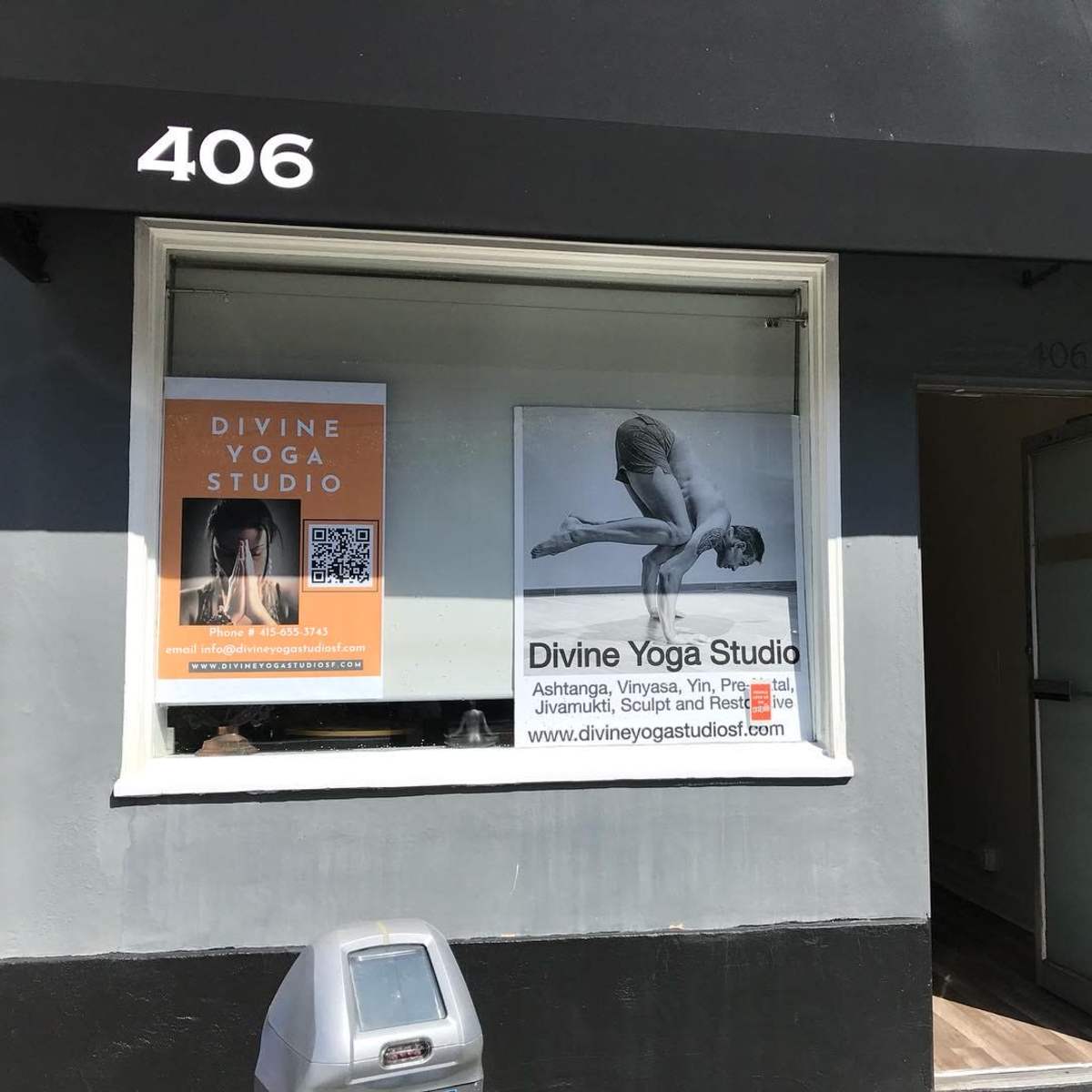 The exterior of a yoga studio with a large window display featuring promotional posters for "Divine Yoga Studio" at the address 406.