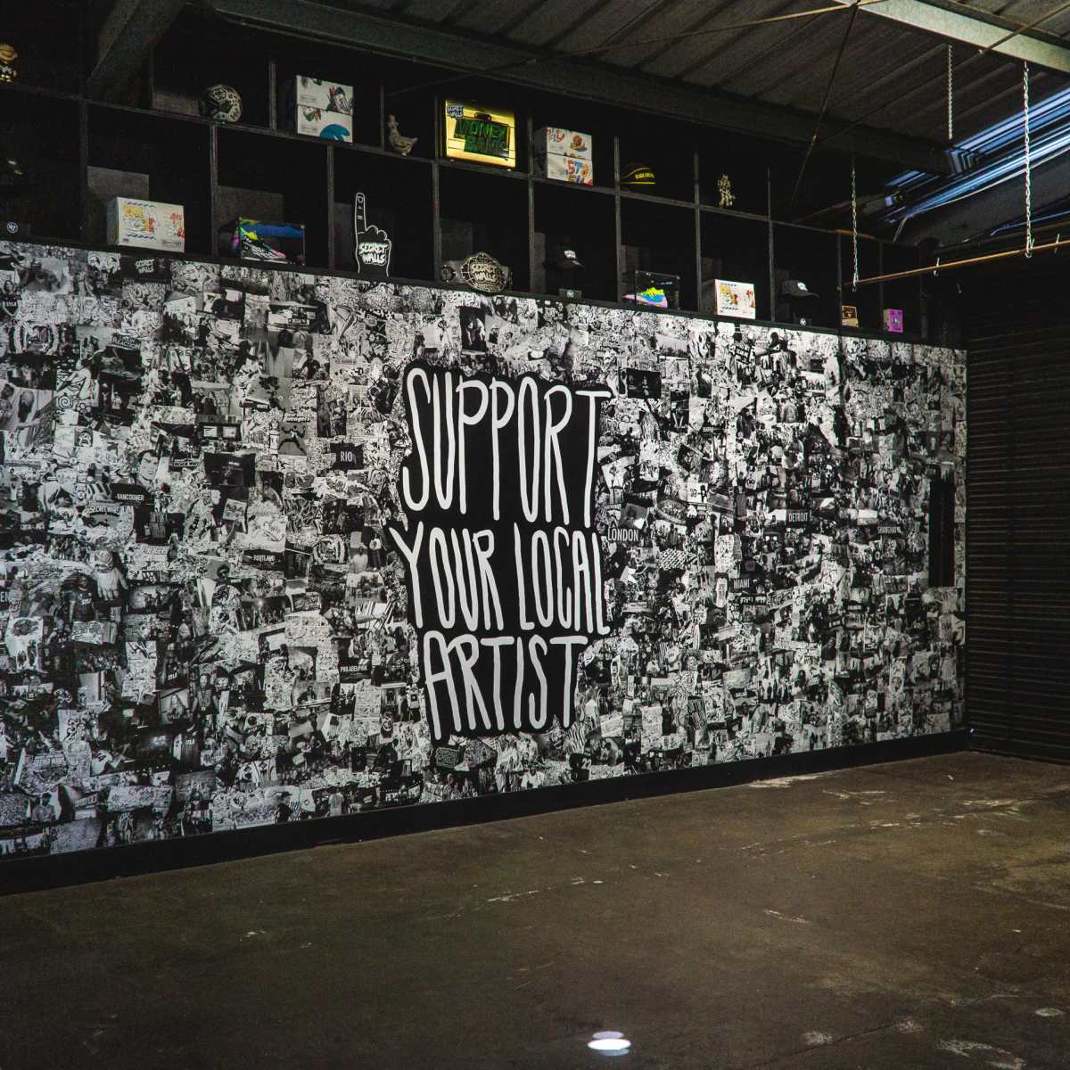 A large mural on a wall featuring the phrase "SUPPORT YOUR LOCAL ARTIST" surrounded by a collage of black-and-white photographs and artwork.