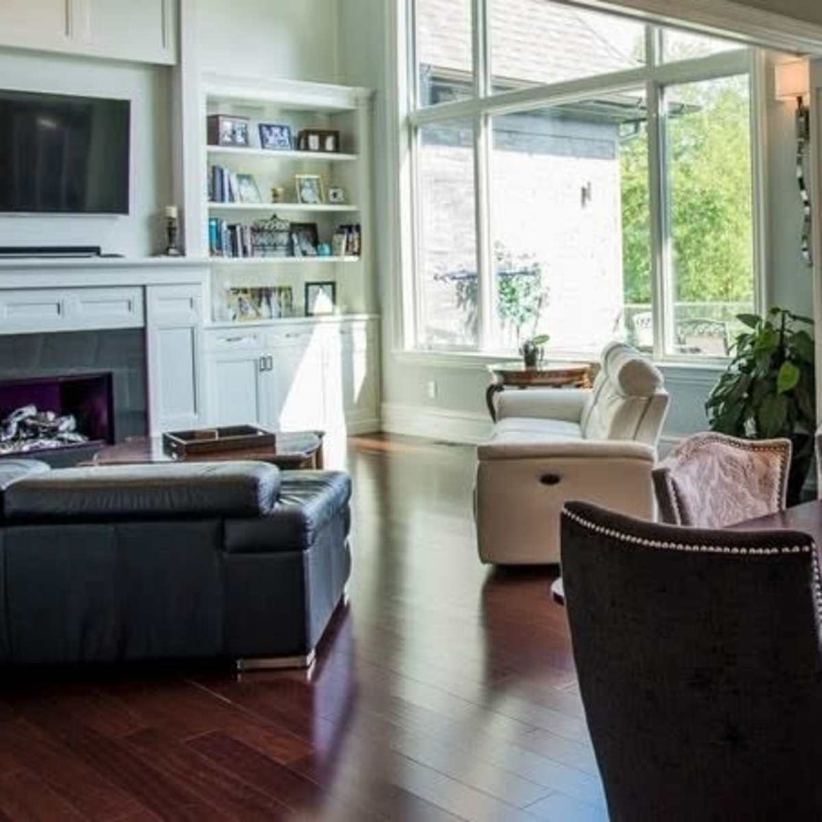 A modern living and dining area with large windows, a wooden dining table, and a seating arrangement featuring a sofa and chairs.