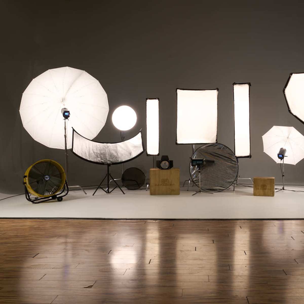 A photography setup with various light modifiers and equipment arranged on a white backdrop.