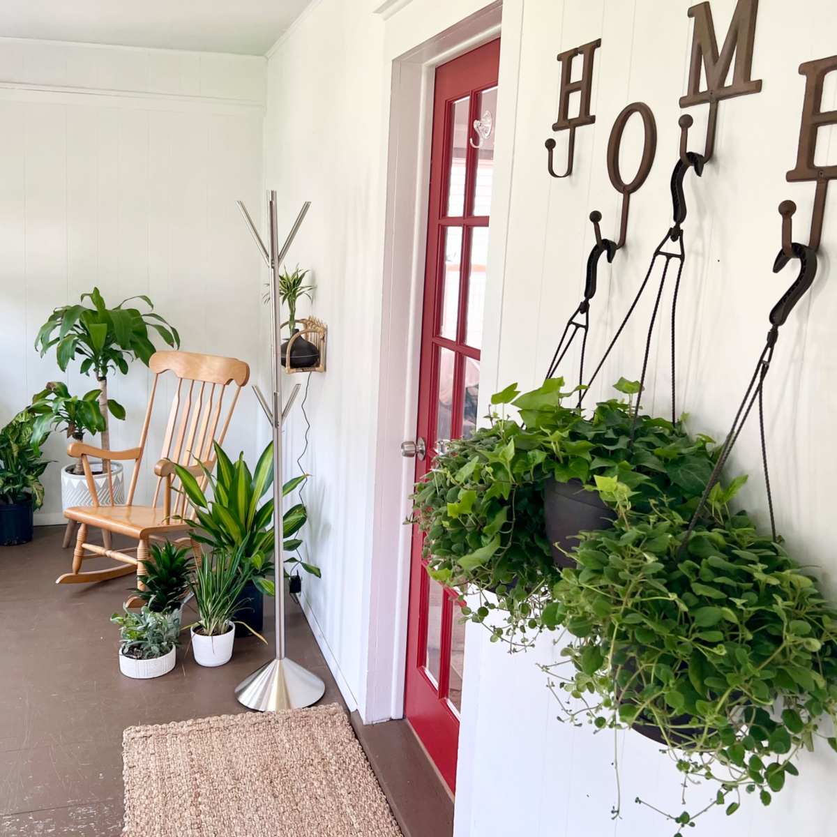 A bright entryway featuring a rocking chair, several potted plants, and a decorative sign spelling "HOME" on the wall.