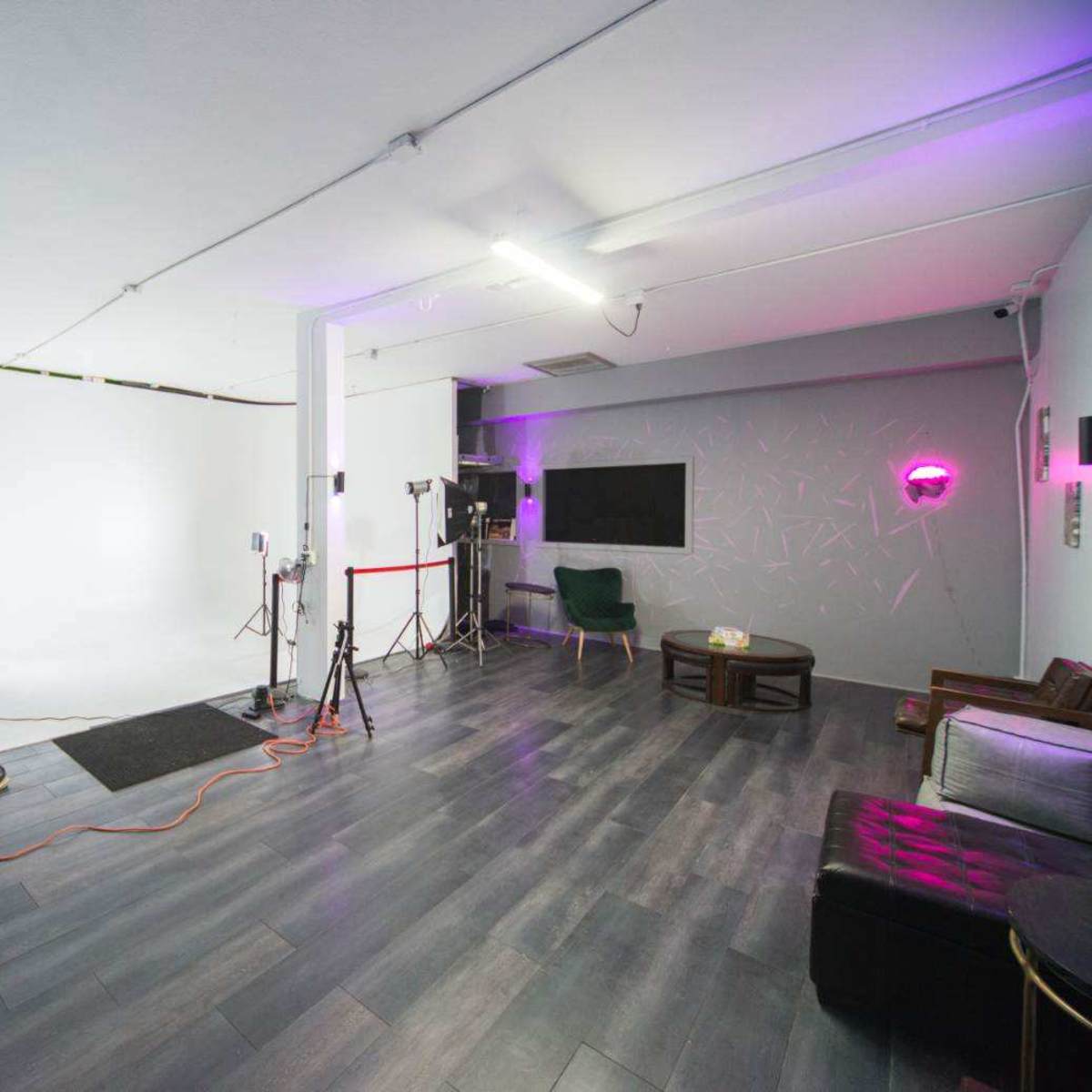 A photography studio with a white backdrop, lighting equipment, and various seating arrangements.