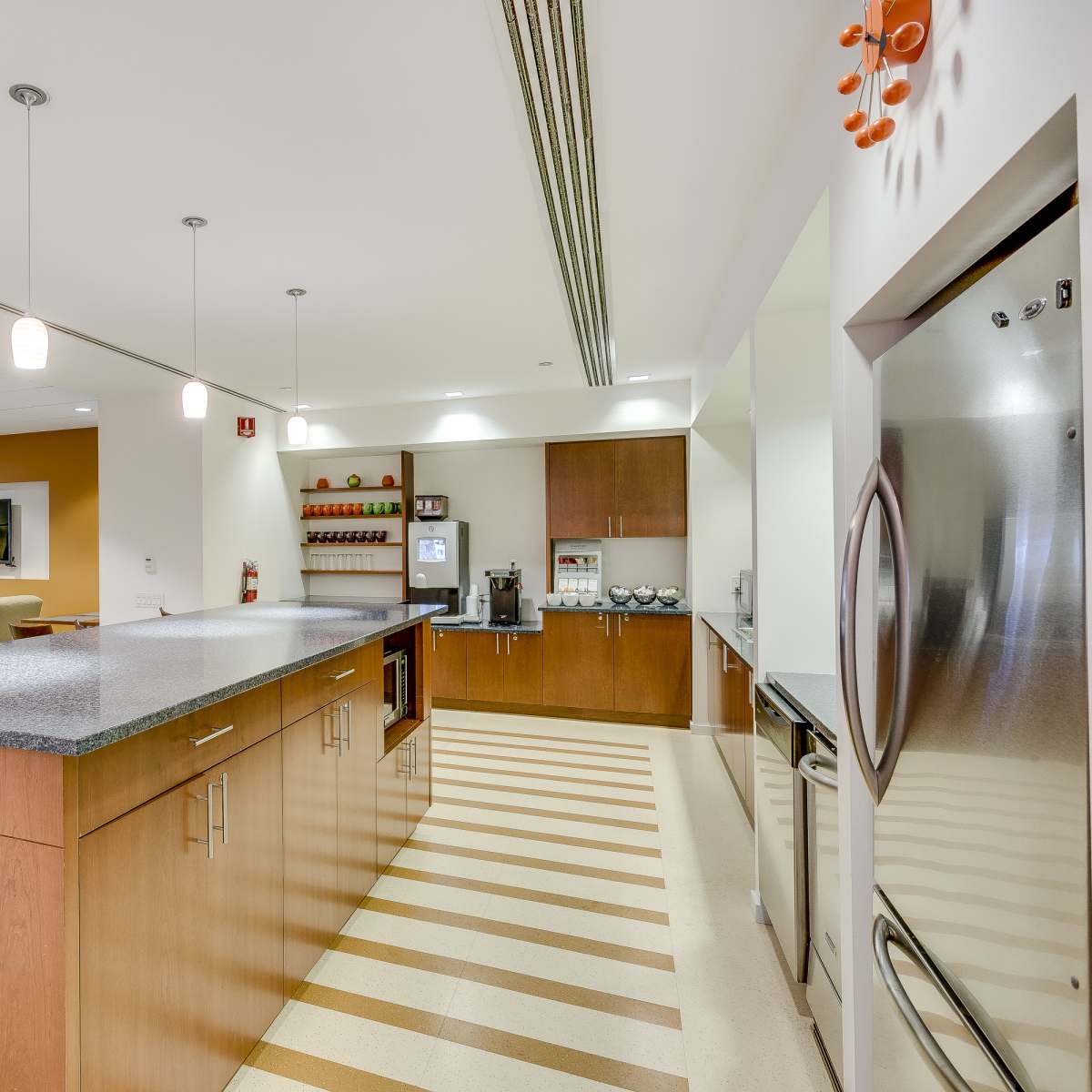 A modern kitchen with wooden cabinets, a countertop, and appliances, situated in a spacious, well-lit room.