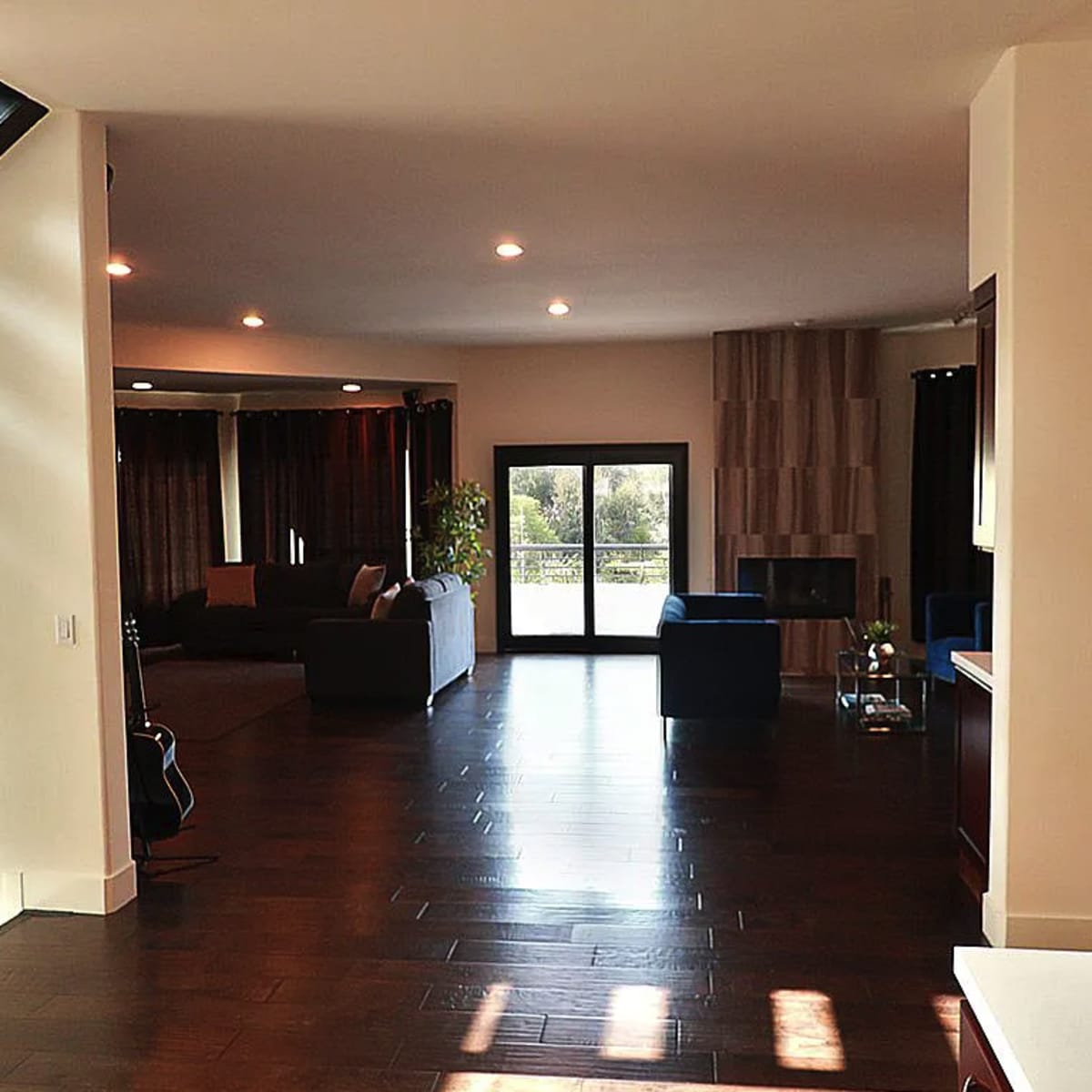 A modern living space with hardwood floors, large windows, and contemporary furniture in a well-lit room.