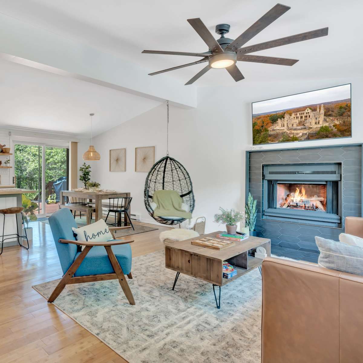 A modern open-concept living space featuring a cozy seating area, a dining table, and a kitchen island, all illuminated by natural light.
