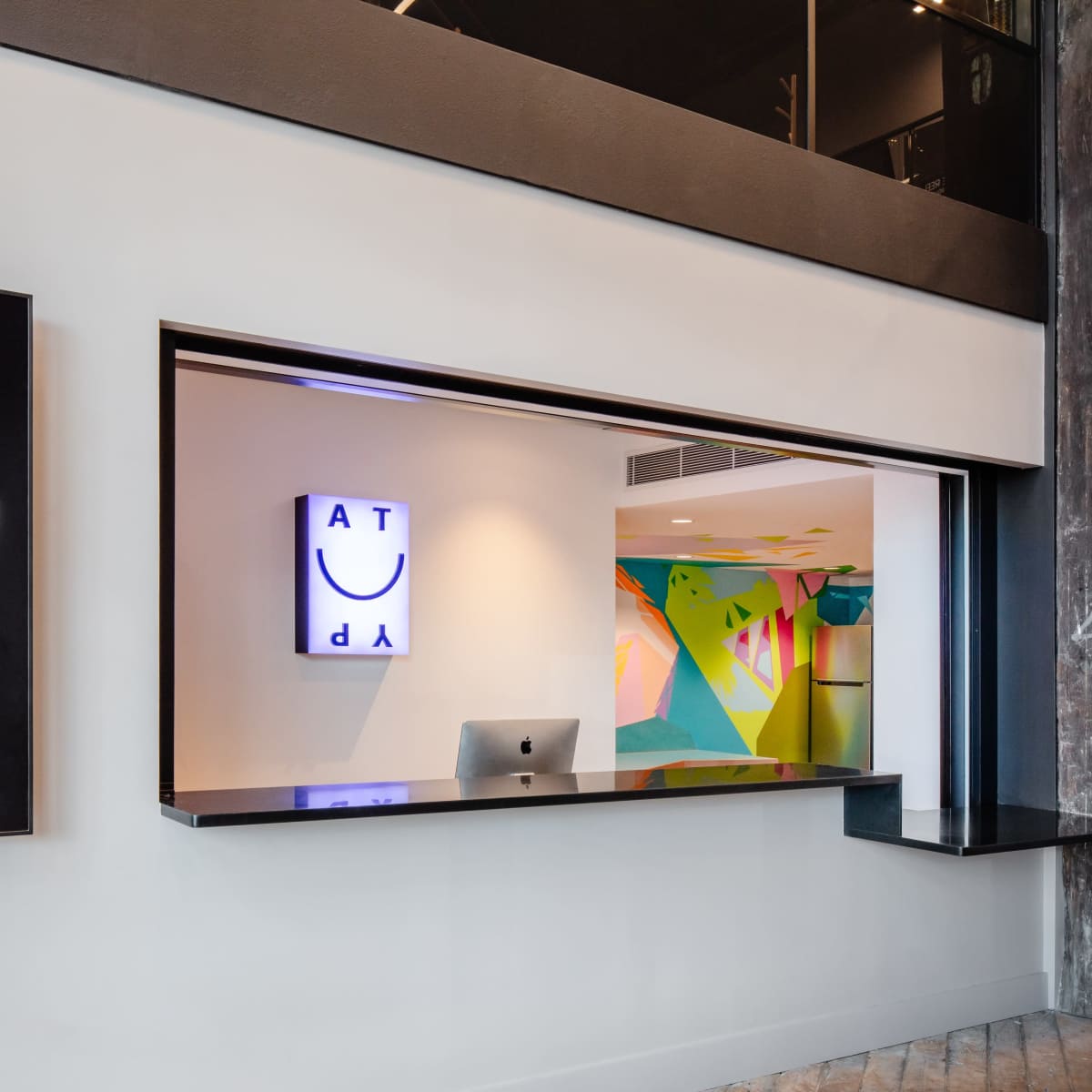 A modern reception area with a sleek black desk and colorful wall art visible behind it.