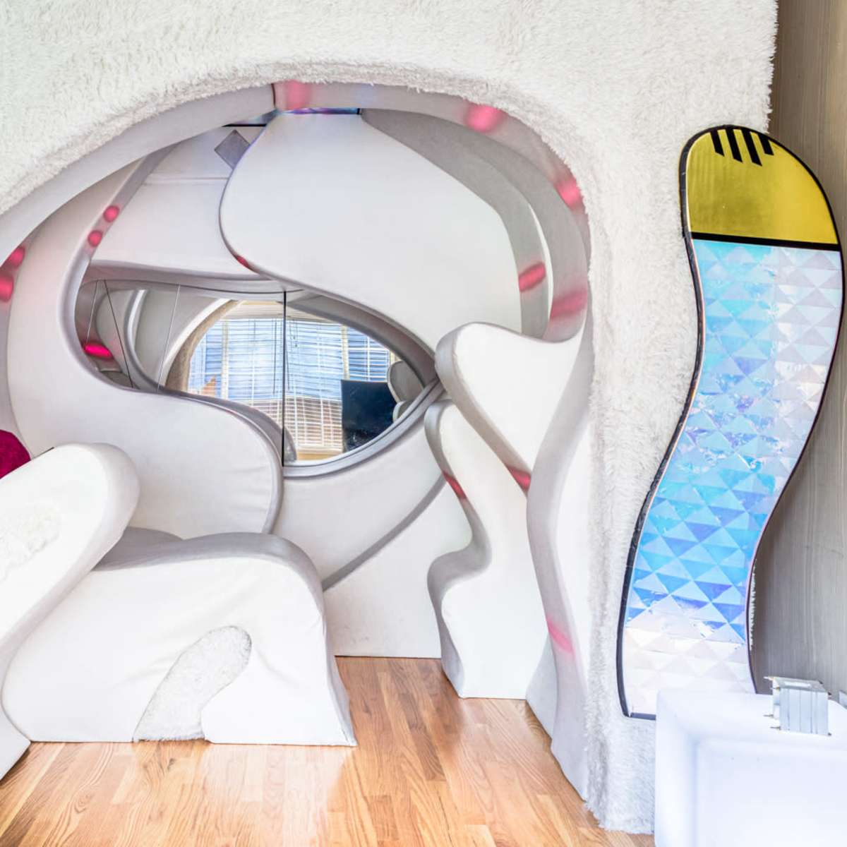A futuristic, soft-walled alcove with a curved seating area and decorative elements in a cozy room.