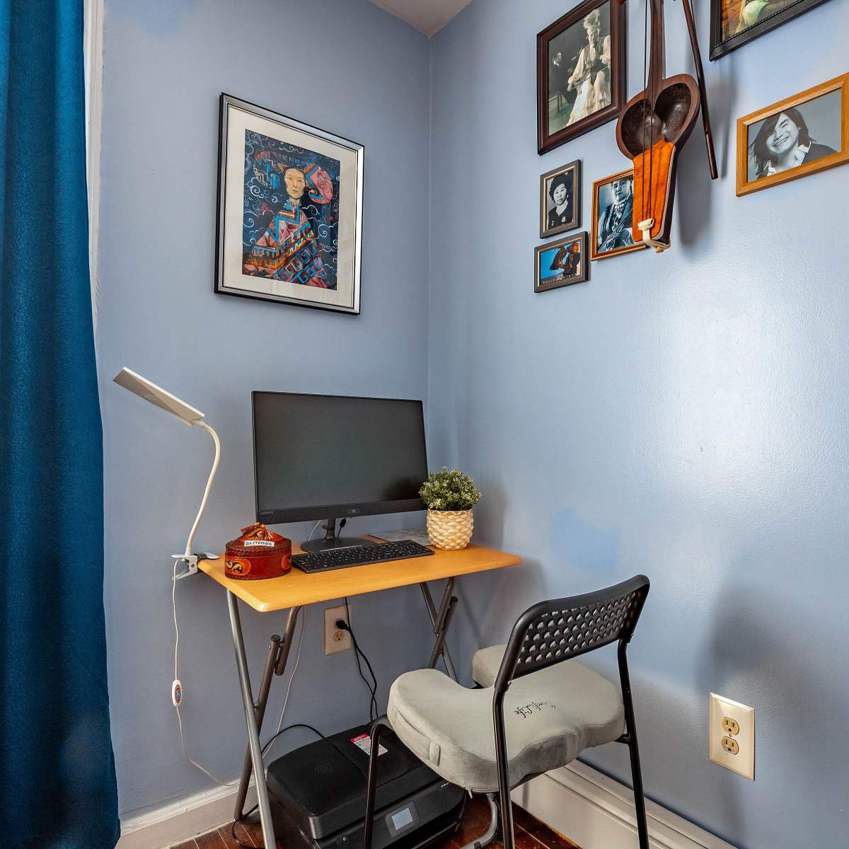 A small workspace features a computer desk with a monitor, a chair, and framed artwork on the walls.