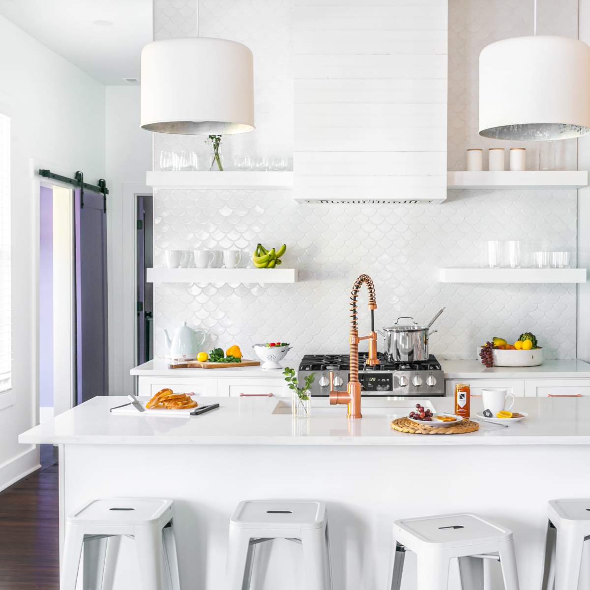 A modern kitchen featuring a white island, stainless steel appliances, a turquoise refrigerator, and colorful floral wallpaper.