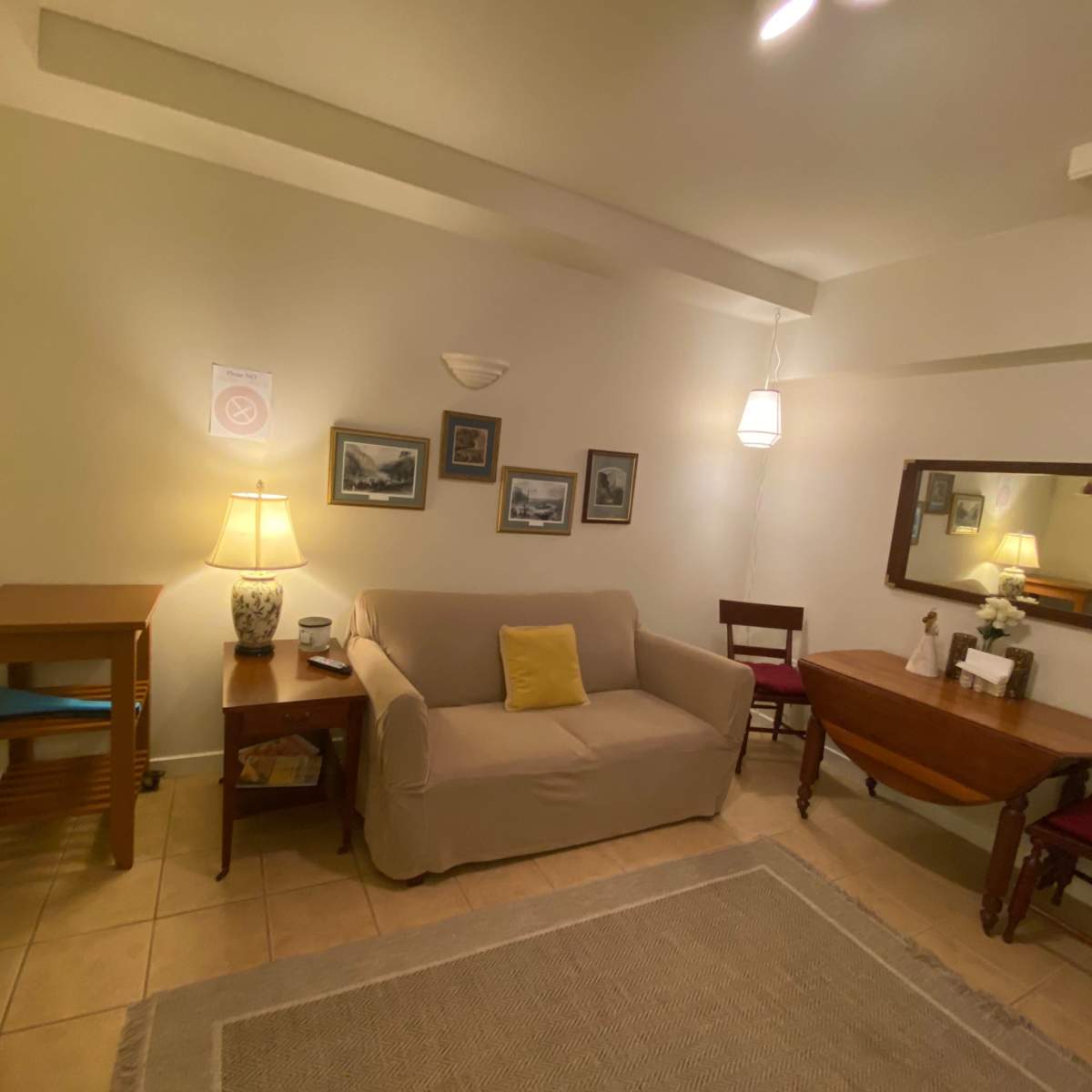 A small living area with a sofa, a wooden table, a lamp, and decorative wall art.