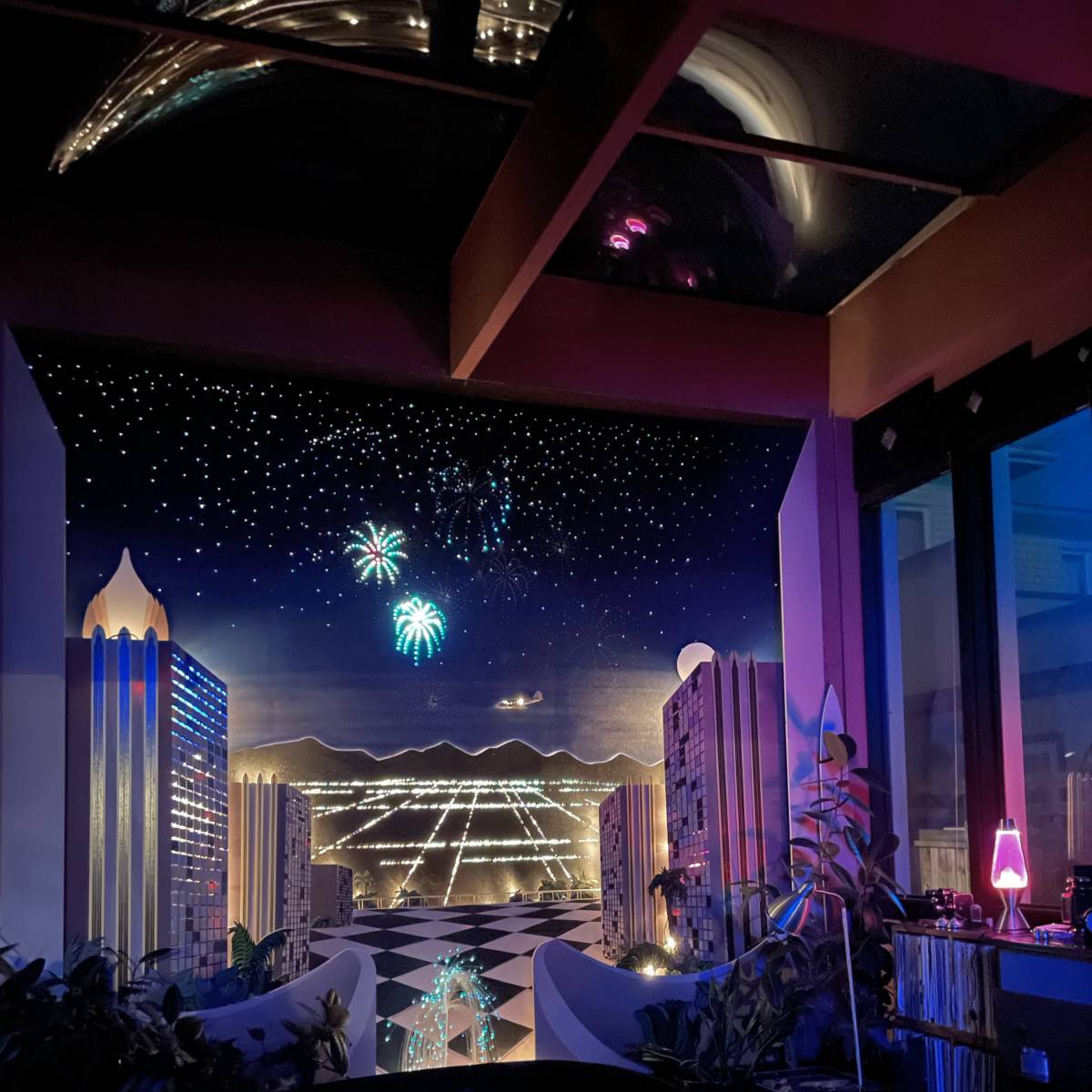 A colorful mural depicting a night cityscape with fireworks in the sky and stylized buildings on either side.