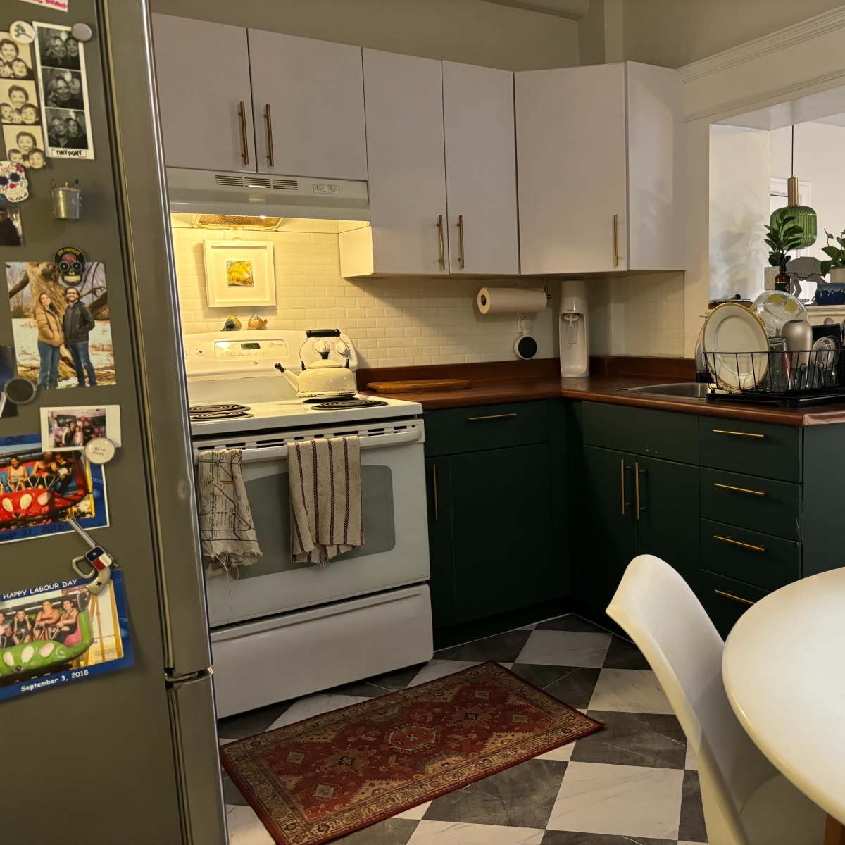 A kitchen with white and green cabinets, a stove, and a dining table on a patterned floor.