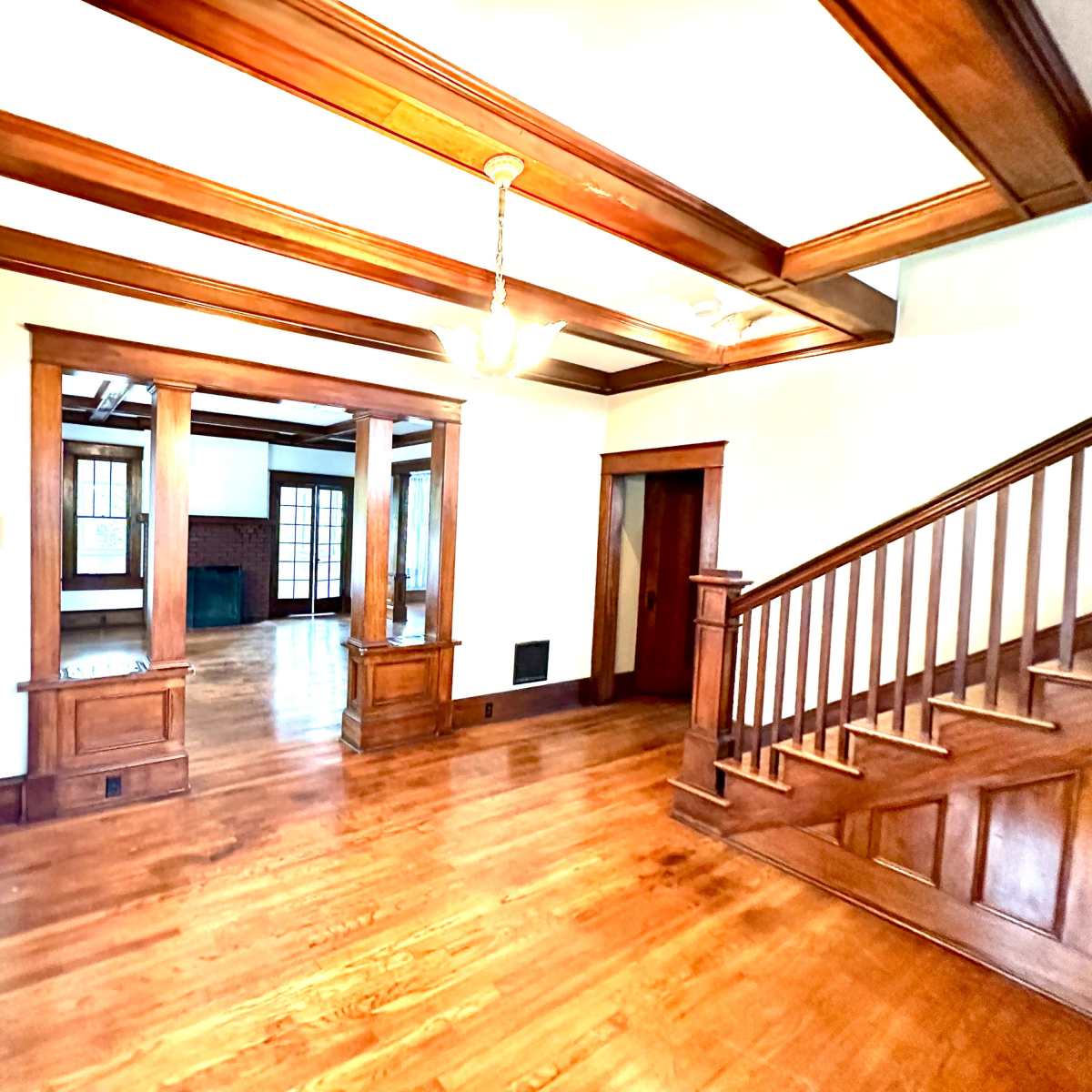 A spacious interior with wooden beams and a staircase leading to an upper level.