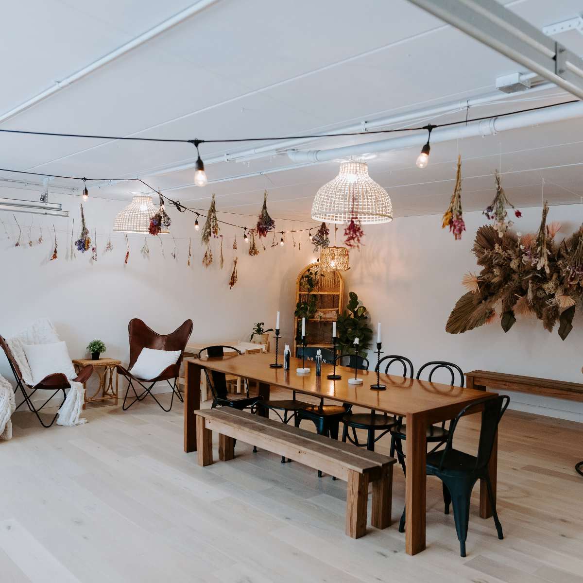 A spacious room with a long wooden dining table surrounded by various seating arrangements and decorative wall hangings.