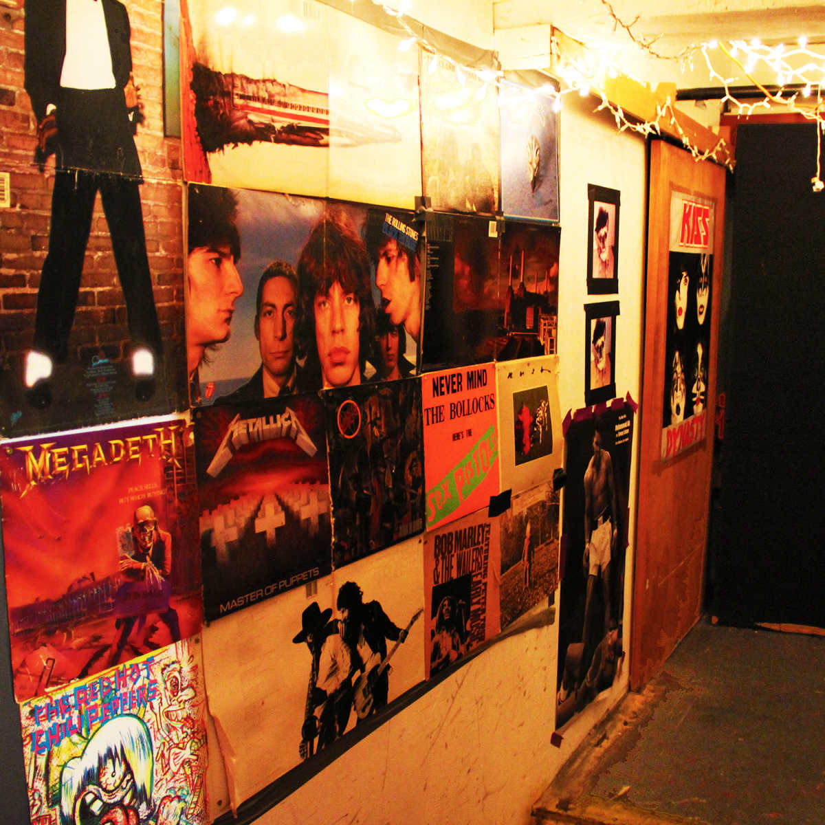 A narrow hallway adorned with various music album posters and string lights.