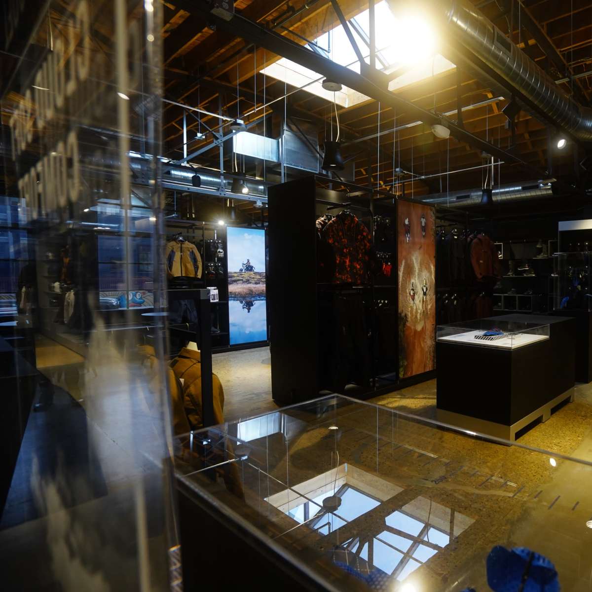 An interior view of a retail store featuring clothing displays, racks, and a sleek, modern layout under soft lighting.