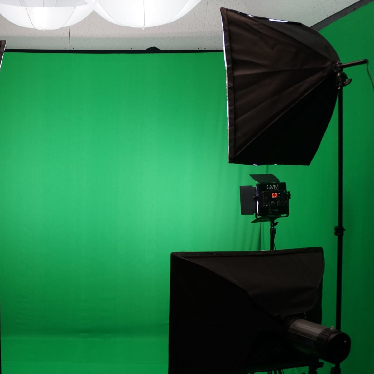 A green screen setup with studio lights on either side, providing an even backdrop for filming or photography.