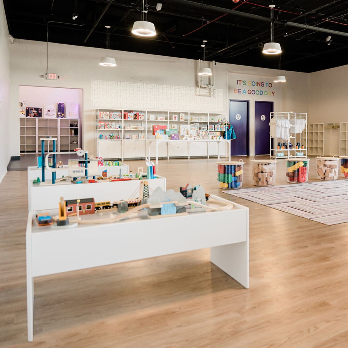 A spacious and organized playroom with various storage units and tables filled with toys and educational materials.