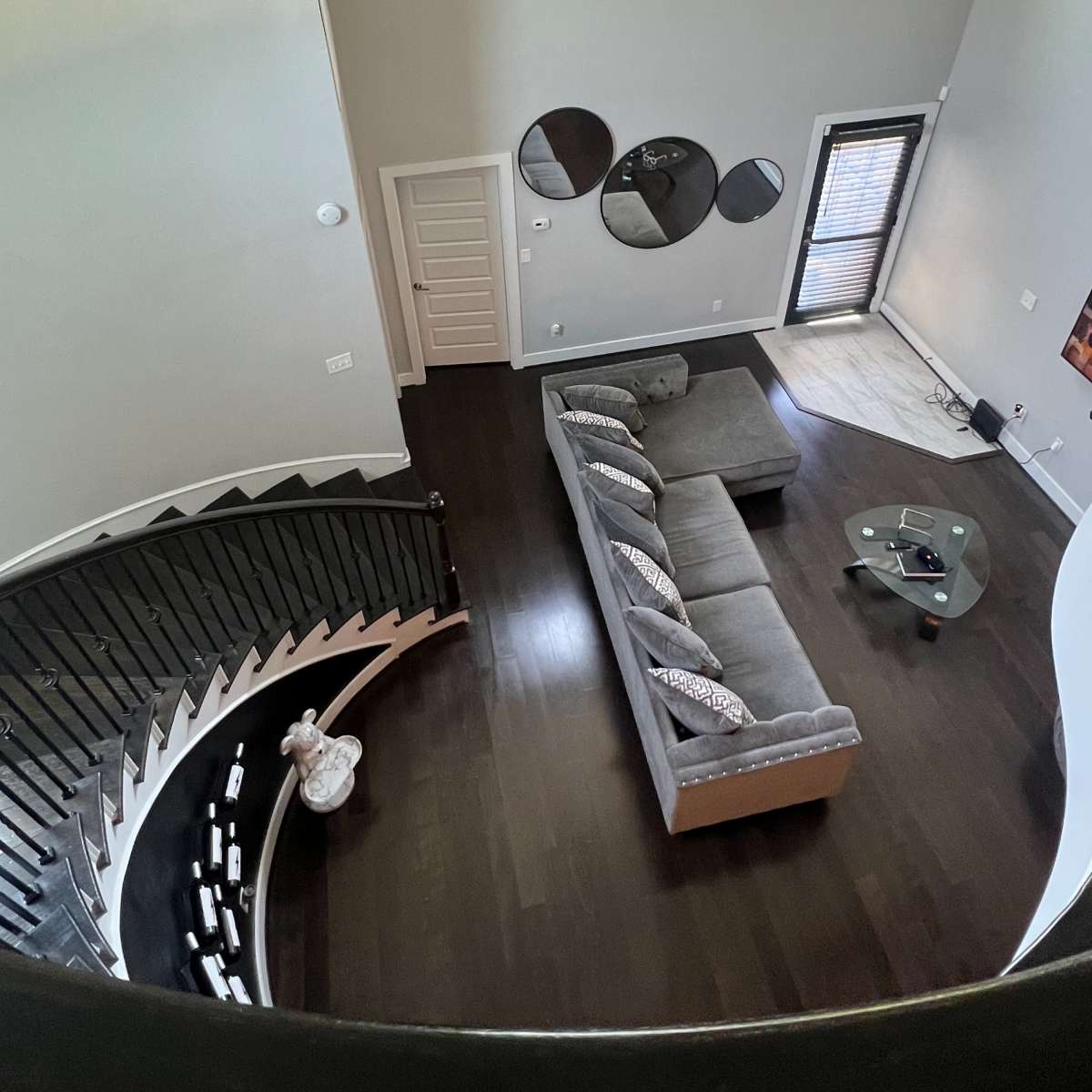 A modern living room with a sectional sofa, a coffee table, and a large window, viewed from an elevated perspective.