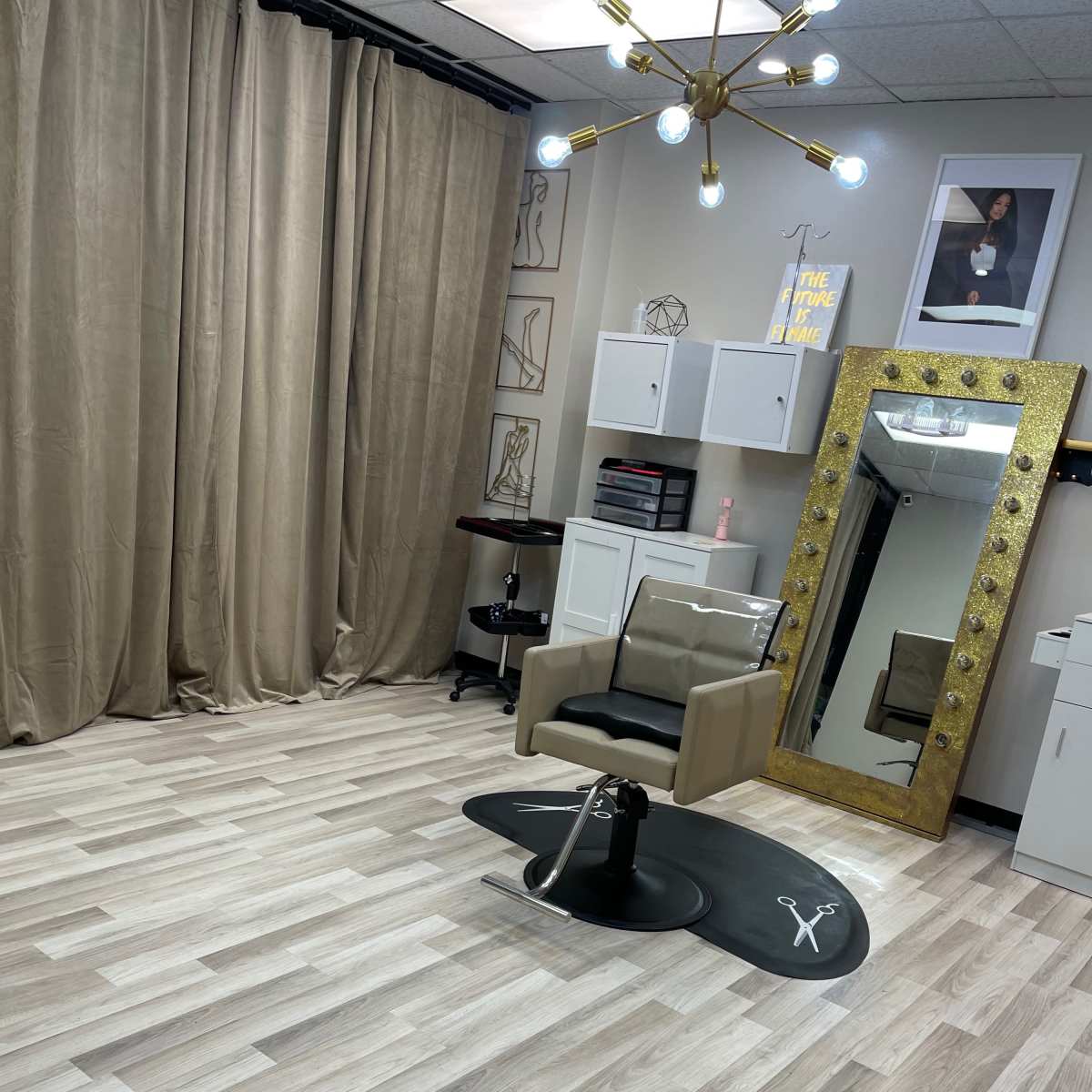 A modern hair salon with a styling chair, a large mirror, and beige curtains draping one side of the room.