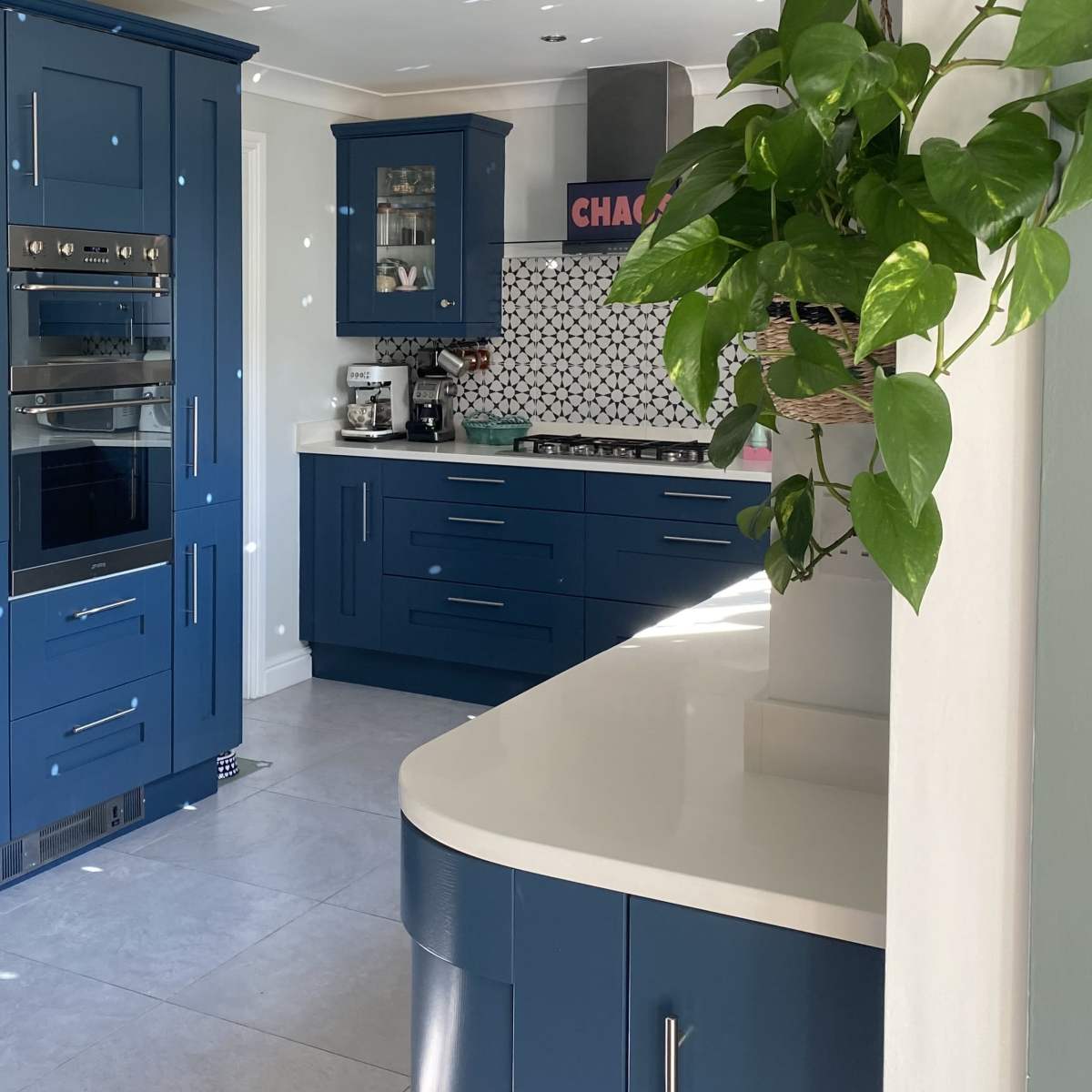 A modern kitchen with blue cabinetry, stainless steel appliances, and a light countertop.