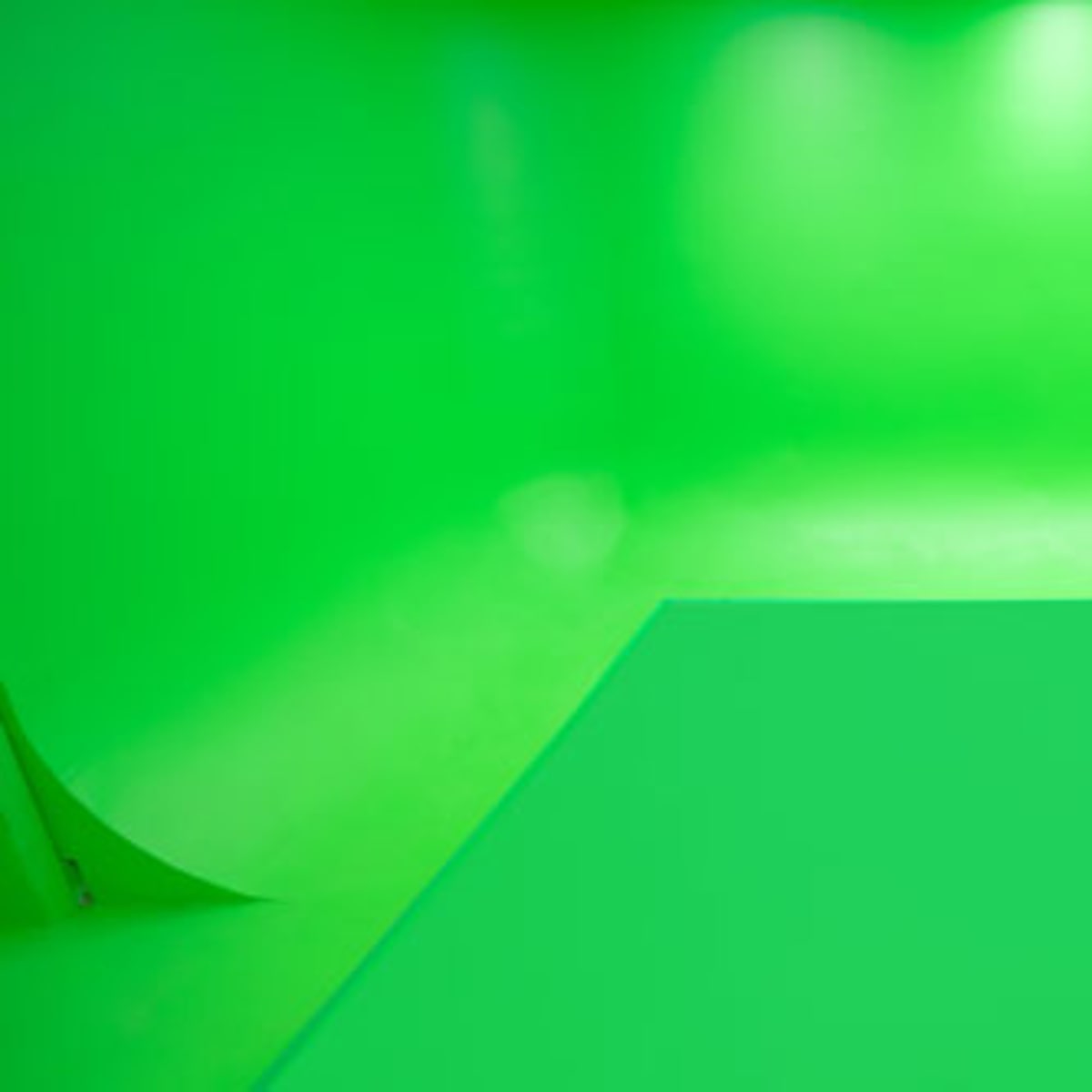 A room with a completely green backdrop and floor, typically used for green screen filming.