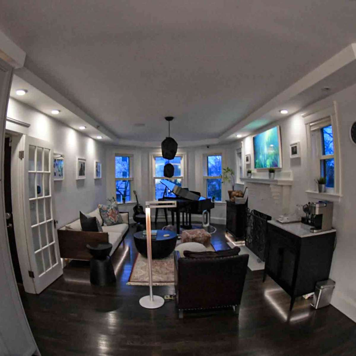 A modern living room featuring a piano, comfortable seating, and large windows providing natural light.