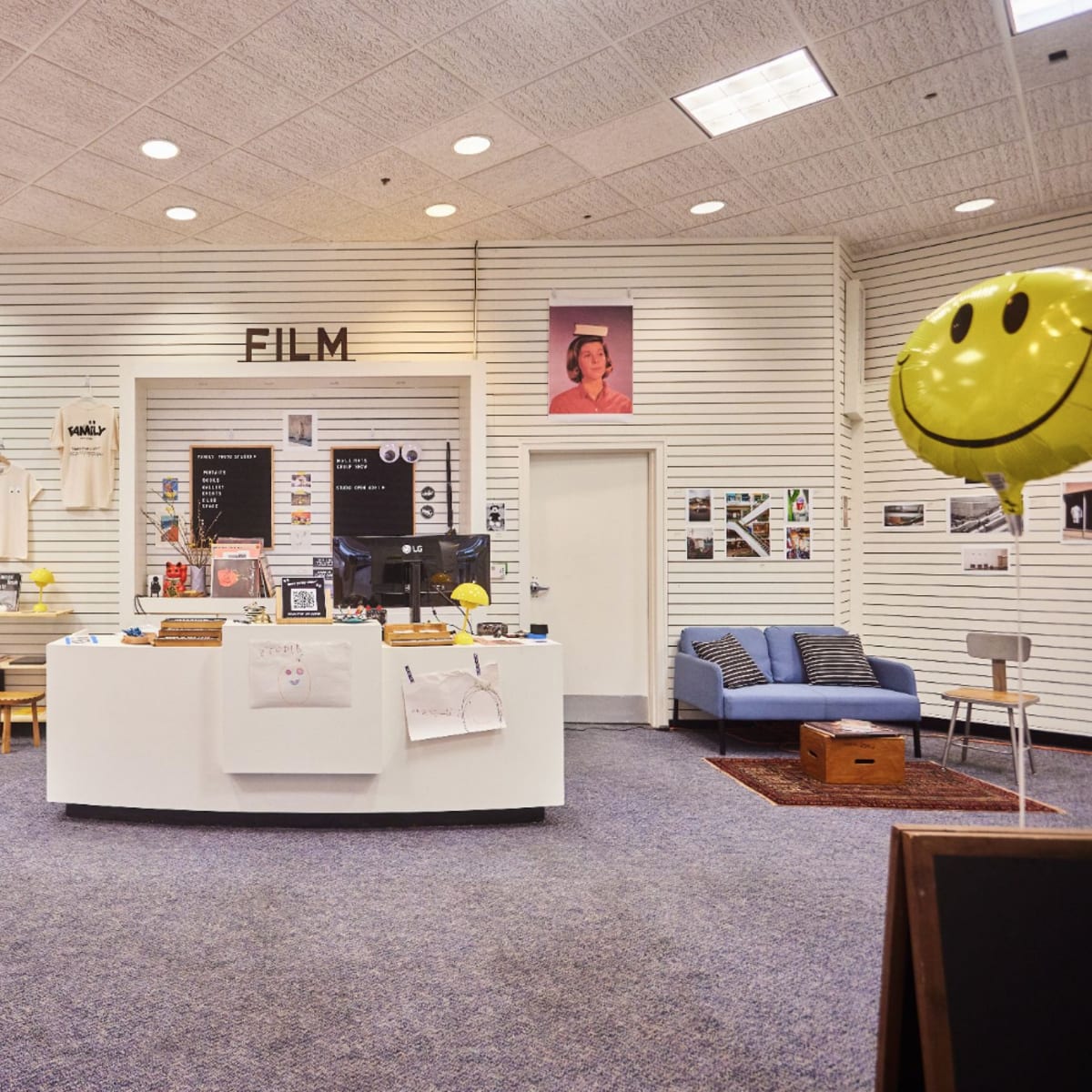 A modern bookstore or display area focused on film, featuring a white circular counter, bookshelves, and various framed images on the walls.