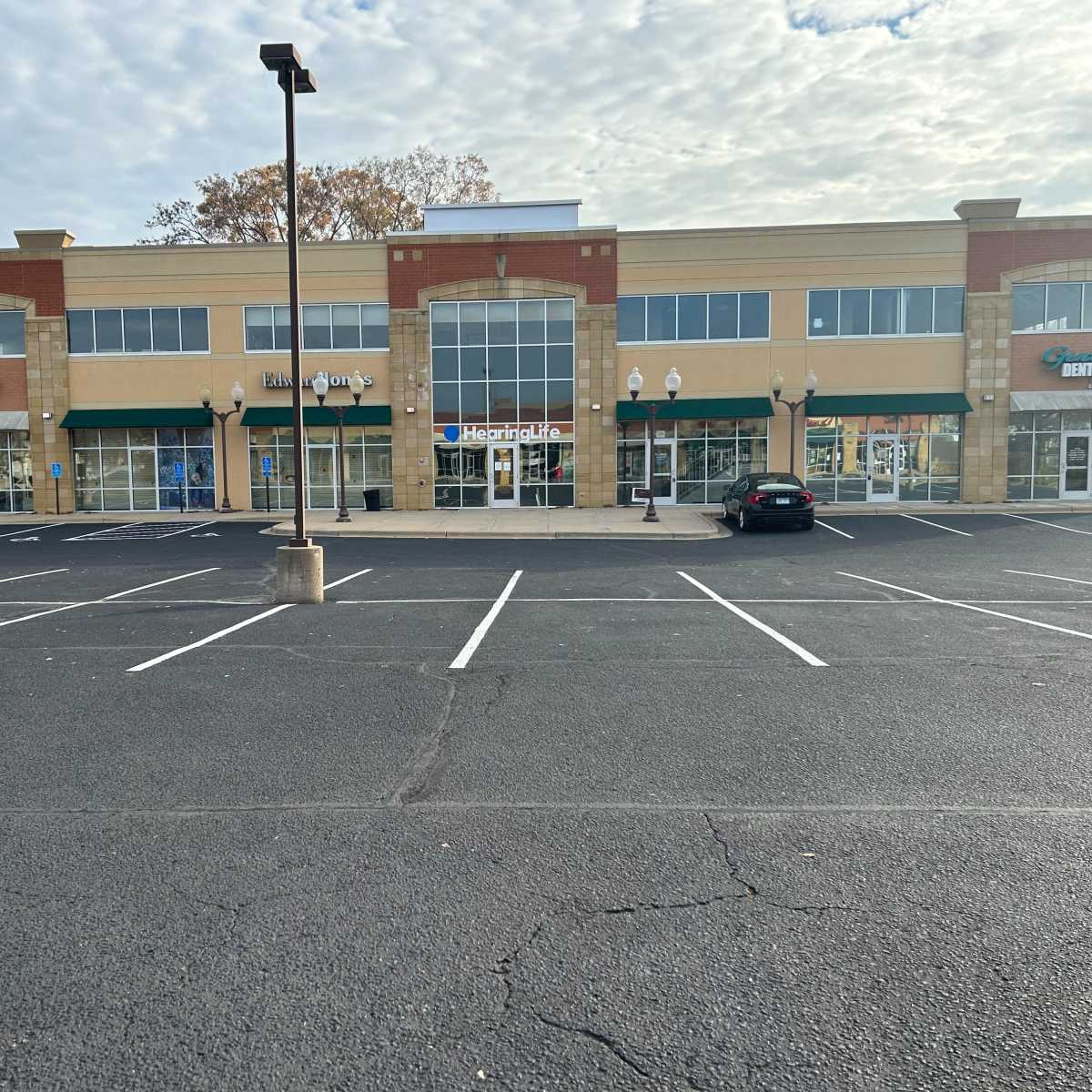 A row of retail storefronts with several businesses, including a restaurant and a grocery store, in a mostly empty parking lot.