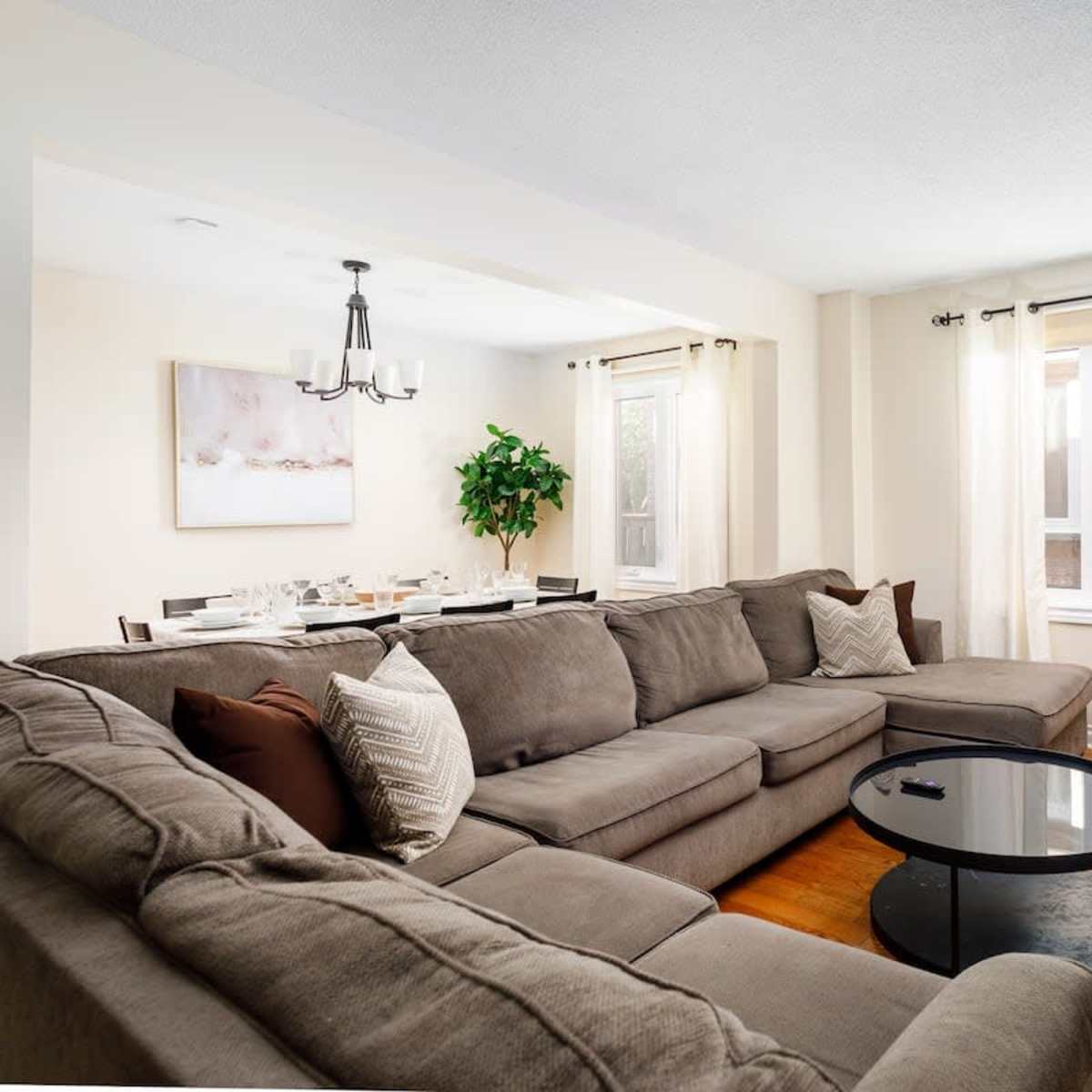 A spacious living room features a large sectional sofa, a glass coffee table, and a dining area with a table set for six.