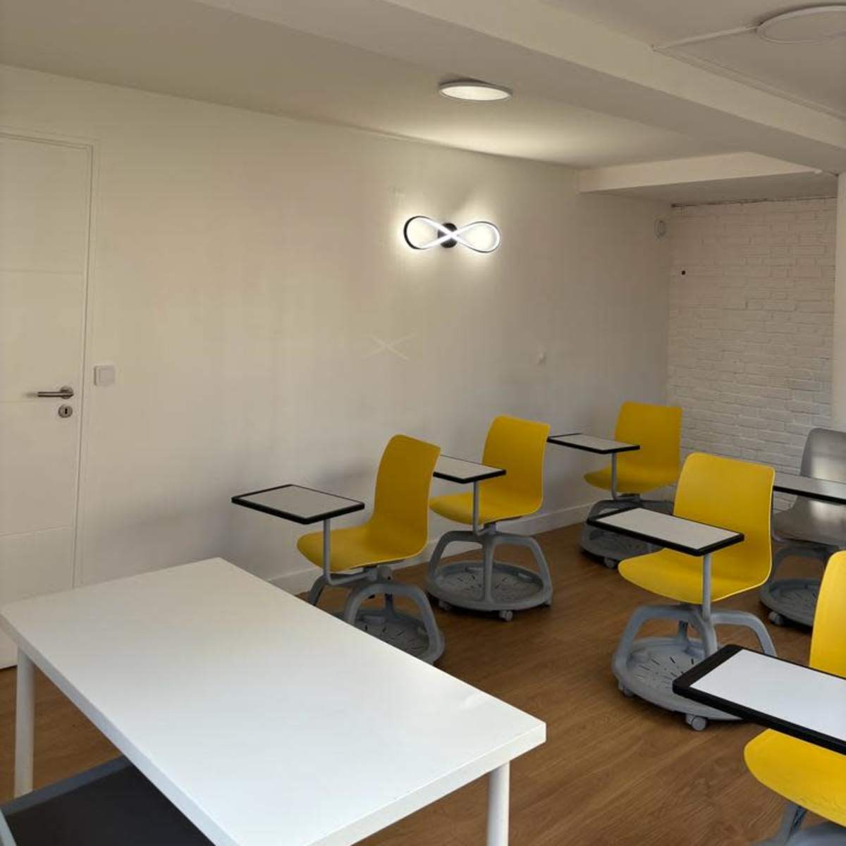 A modern classroom with yellow chairs and desks arranged in a minimalist design.