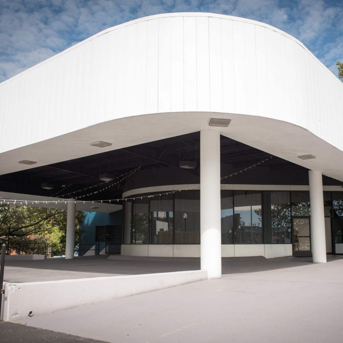 The building features a curved, white exterior with large windows and is supported by several columns.
