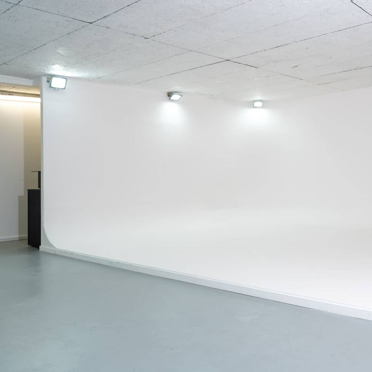 A minimalist white studio space with a smooth floor and curved backdrop.