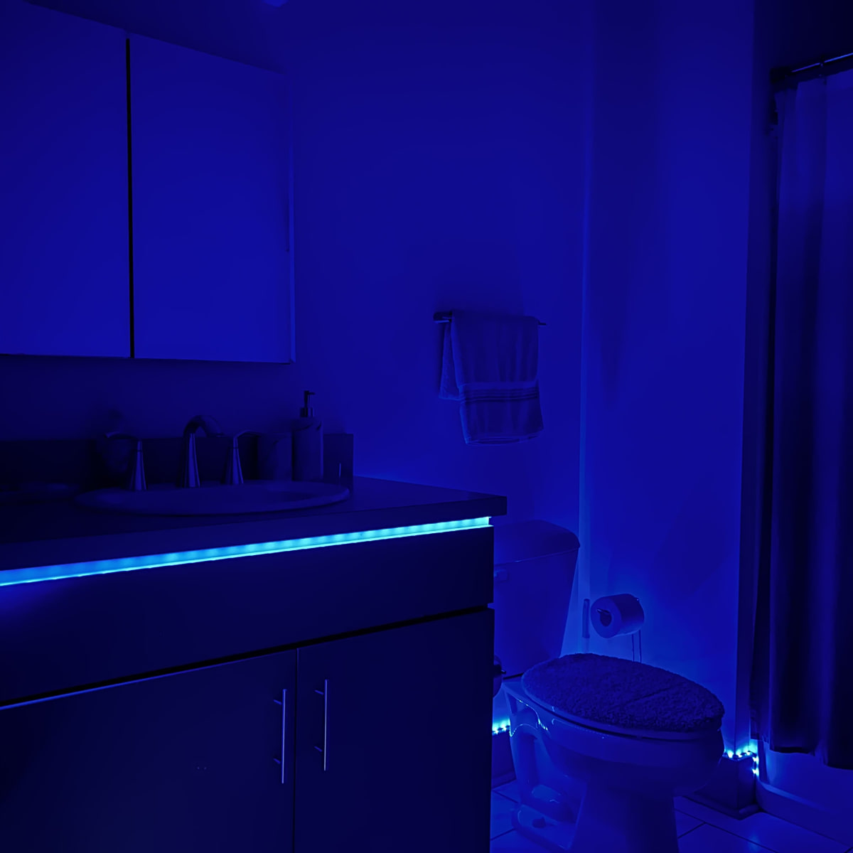 The bathroom features blue LED lighting illuminating the countertop and the base of the toilet.
