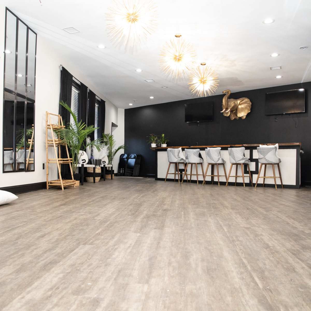 A spacious, modern interior with hardwood flooring, a seating area featuring stools at a bar-like counter, and decorative plants.