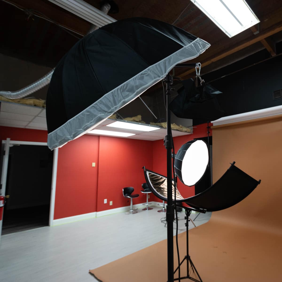 A photography studio setup with various softbox lights and a large brown backdrop.