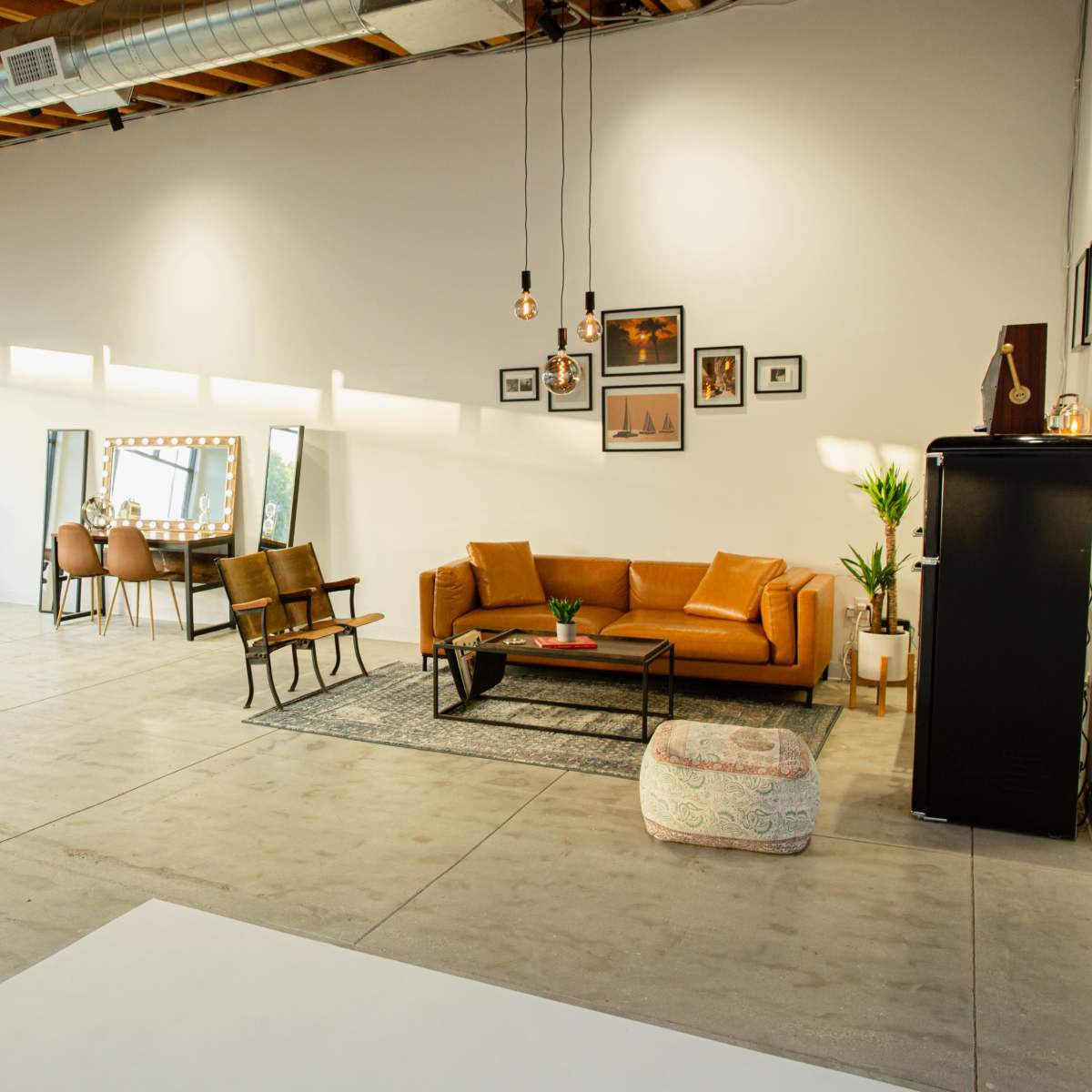 A spacious, modern interior with a living area featuring a brown sofa, a small table, and decorative mirrors against a well-lit wall.