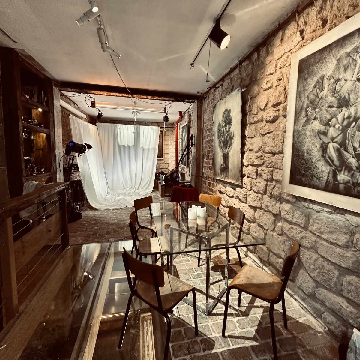 A rustic room with stone walls, wooden furniture, and a backdrop for photography or events.