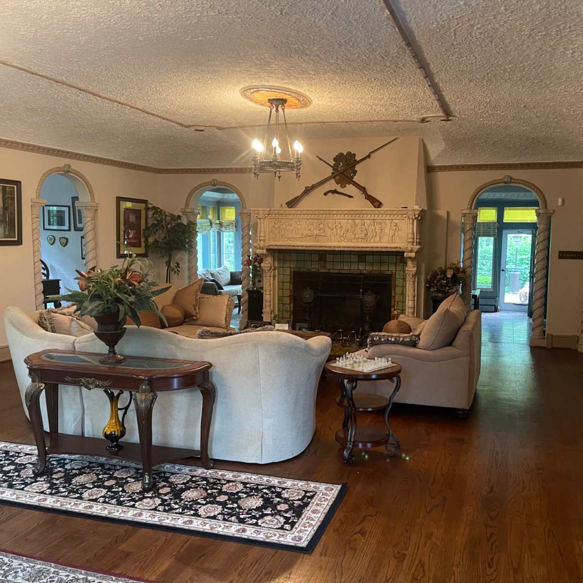 A spacious living room with two sofas arranged around a central coffee table, featuring a decorative fireplace and framed artwork on the walls.