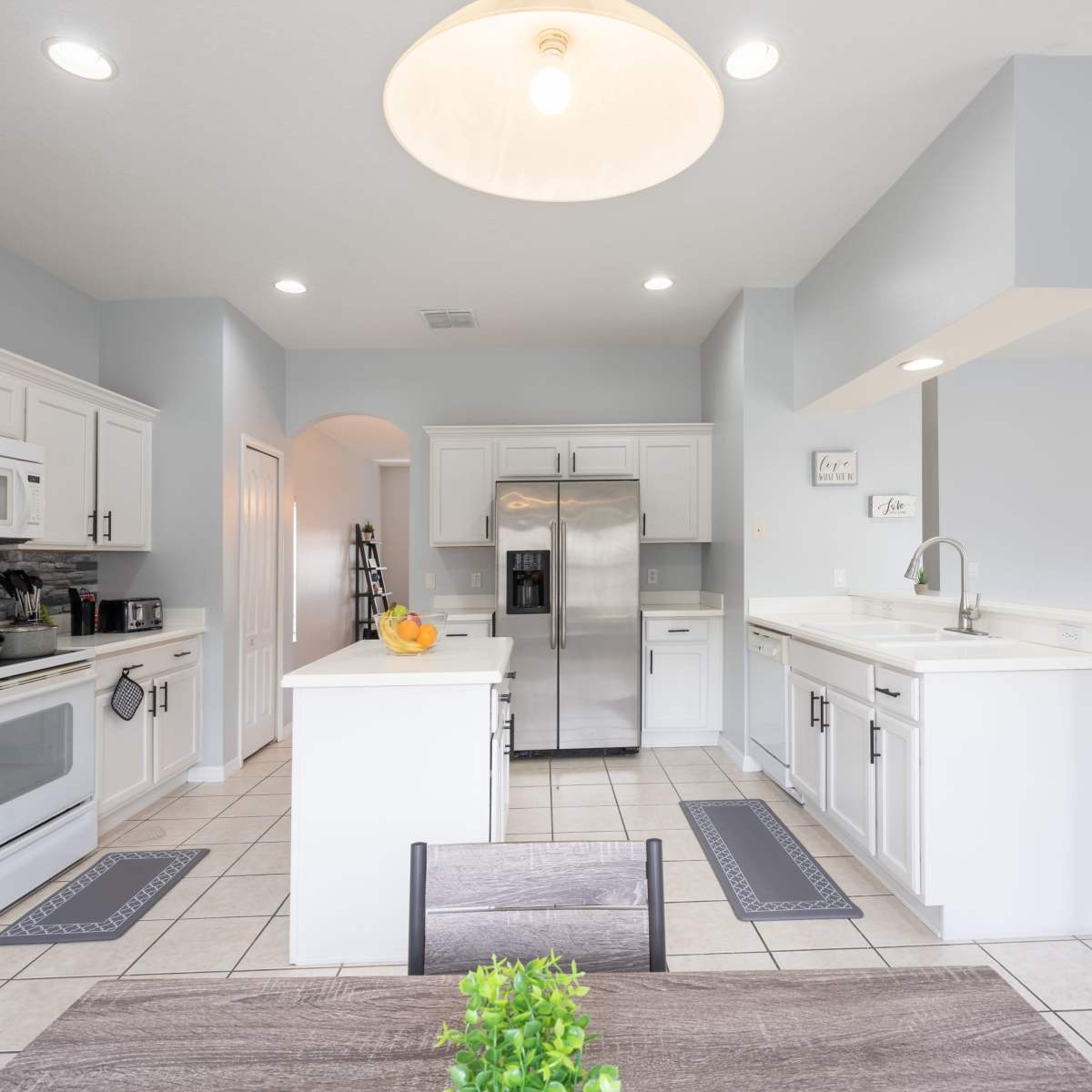 A modern kitchen features white cabinetry, stainless steel appliances, and a central island with bar seating.