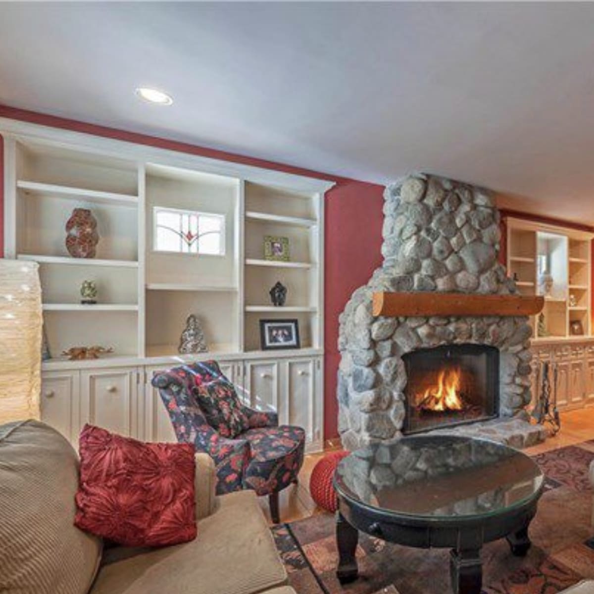 The living room features a stone fireplace, built-in shelves, and a large television mounted on the wall.