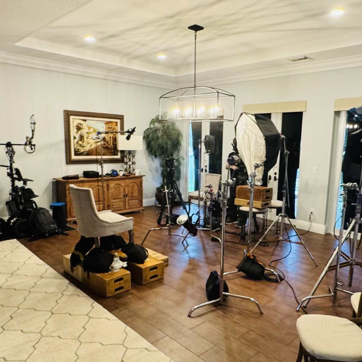 A photography studio setup in a room with various lighting equipment, cameras, and furniture arranged for a shoot.