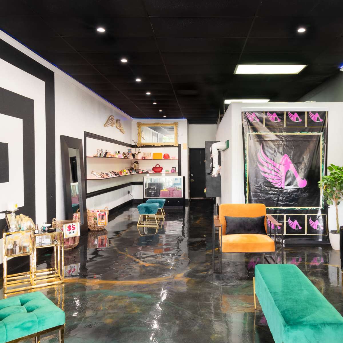 A modern interior of a boutique with a glossy black floor, black and white geometric wall designs, and seating areas featuring green and black chairs.