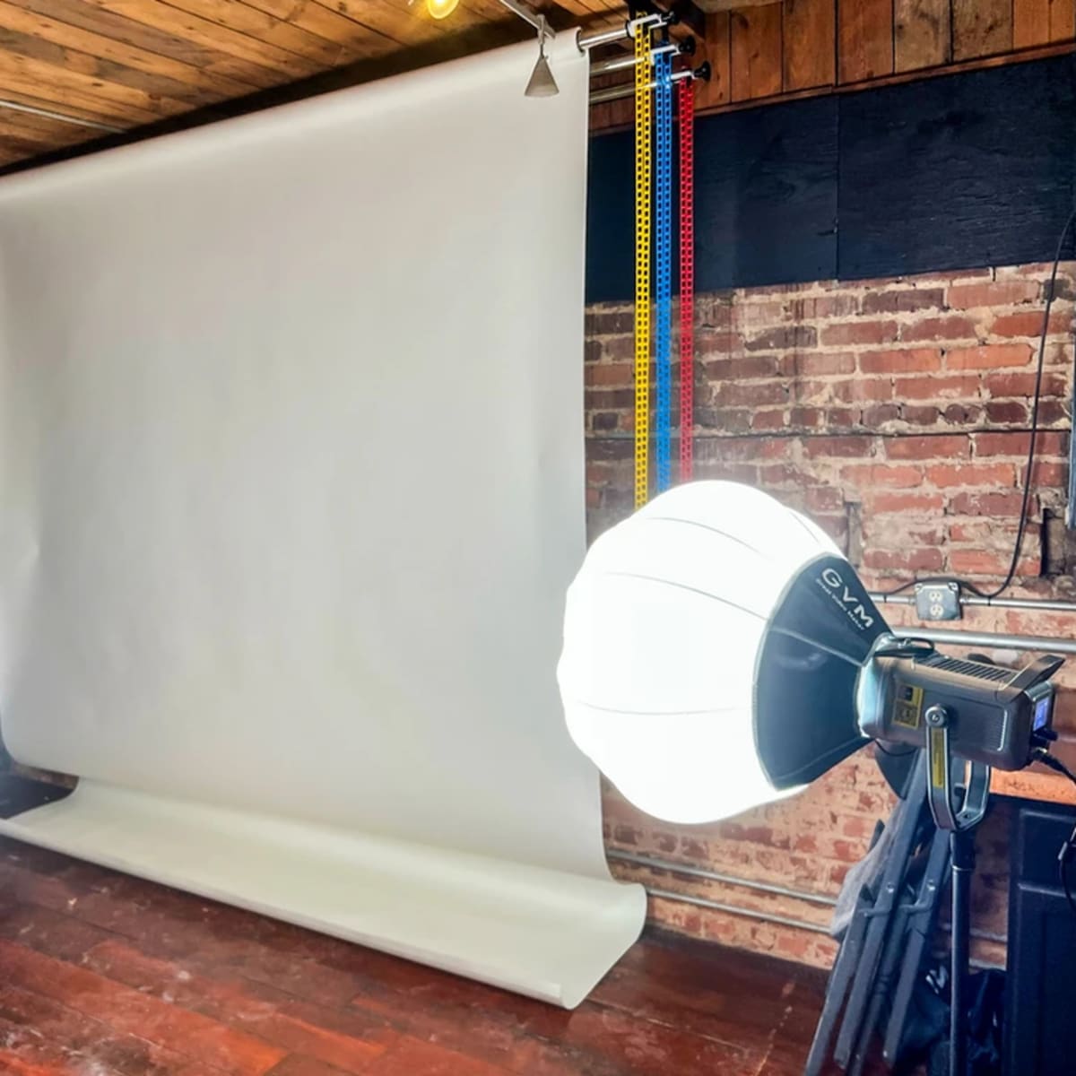 A photography studio setup with a white backdrop and two light sources on either side.