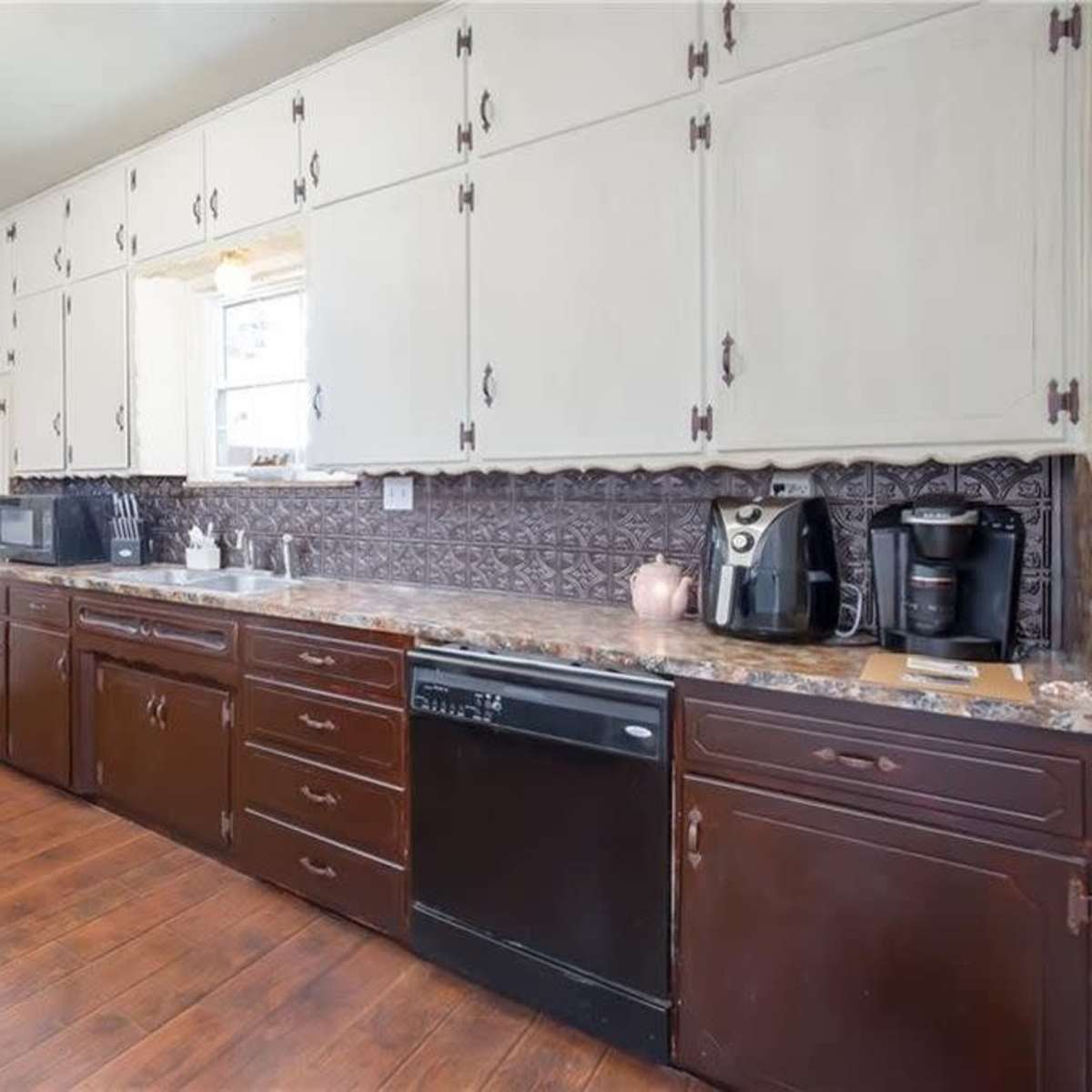 A kitchen with dark wooden cabinets, a granite countertop, and various appliances including a coffee maker and a microwave.