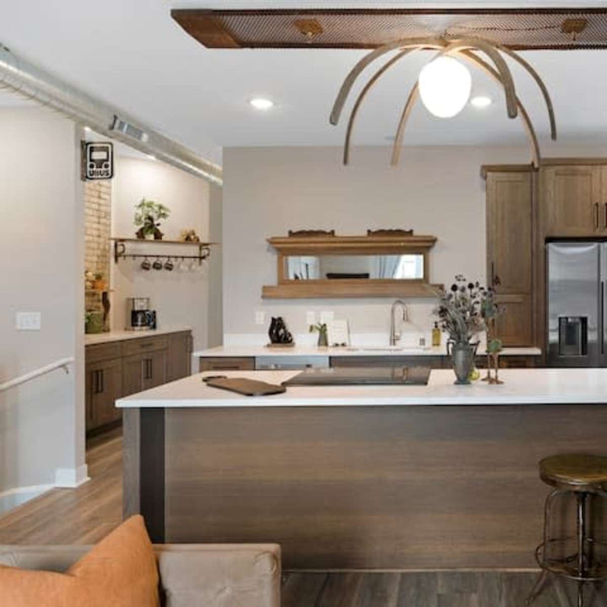 A modern kitchen with wooden cabinets, a large island featuring a white countertop, and a stainless steel refrigerator.