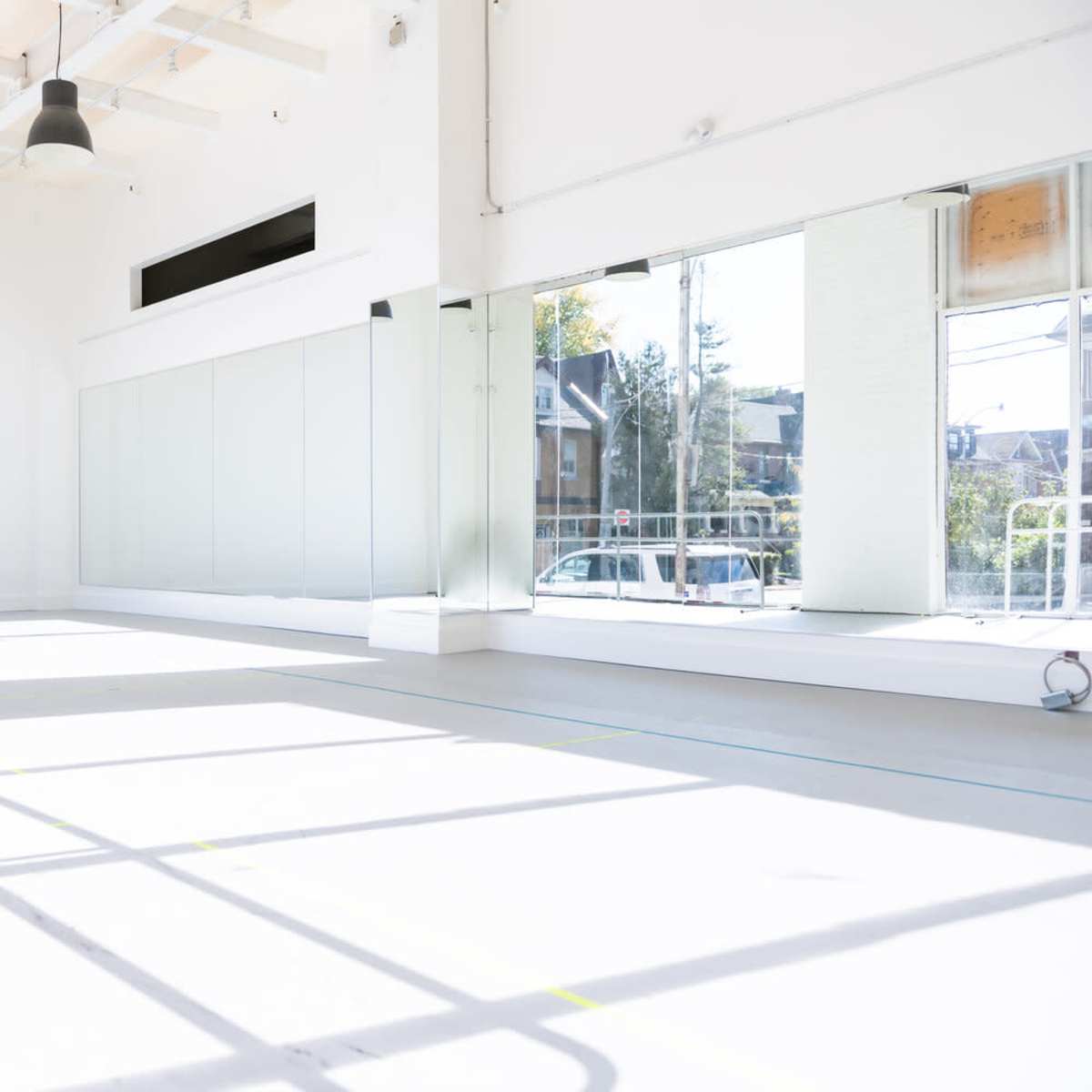A spacious interior with large windows, black pendant lights, and minimal furniture.