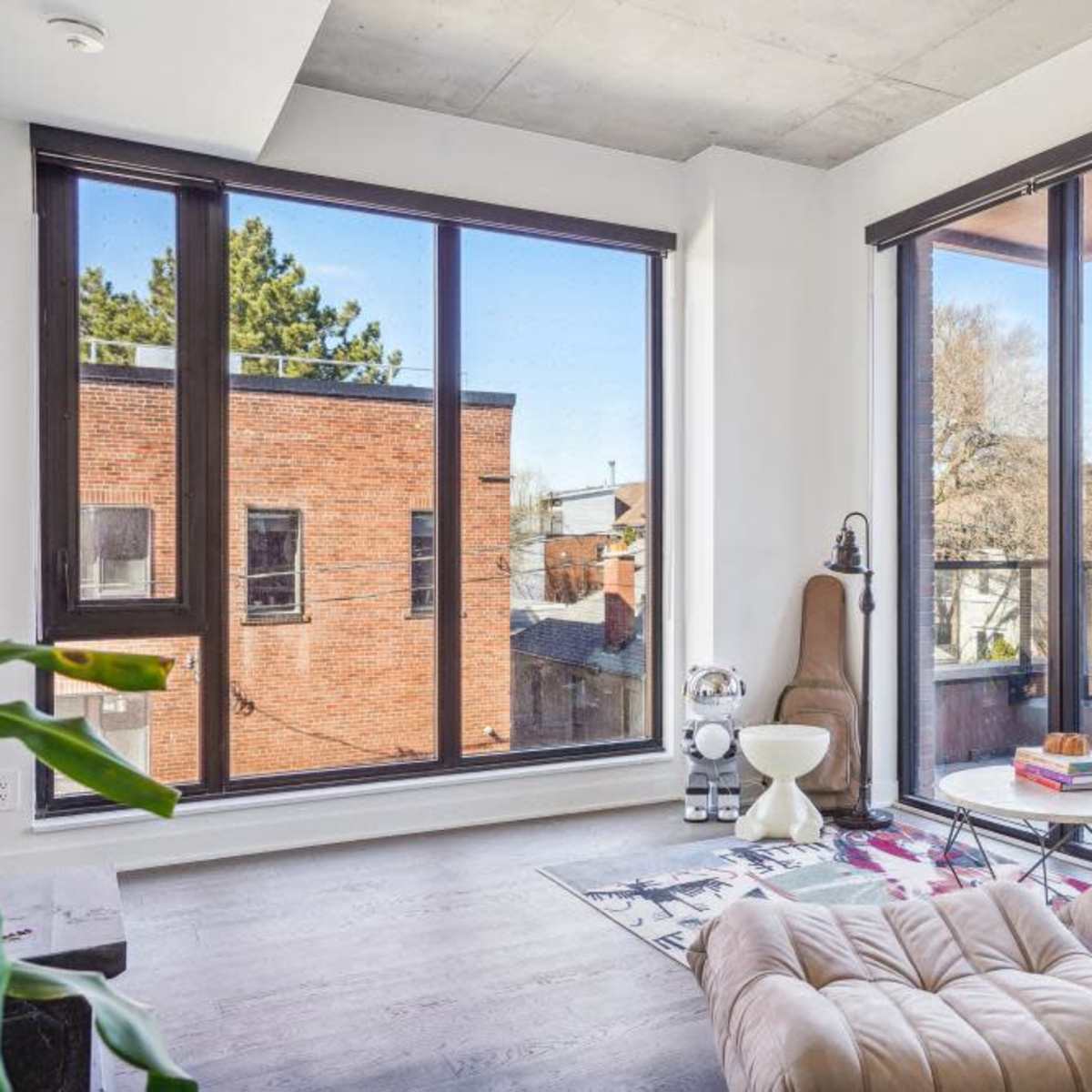 A modern living room with large windows allowing natural light to fill the space, featuring a cozy chair and a small table.