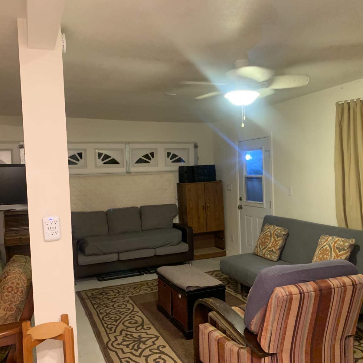 A living room with various seating options, a television, and a door leading outside.