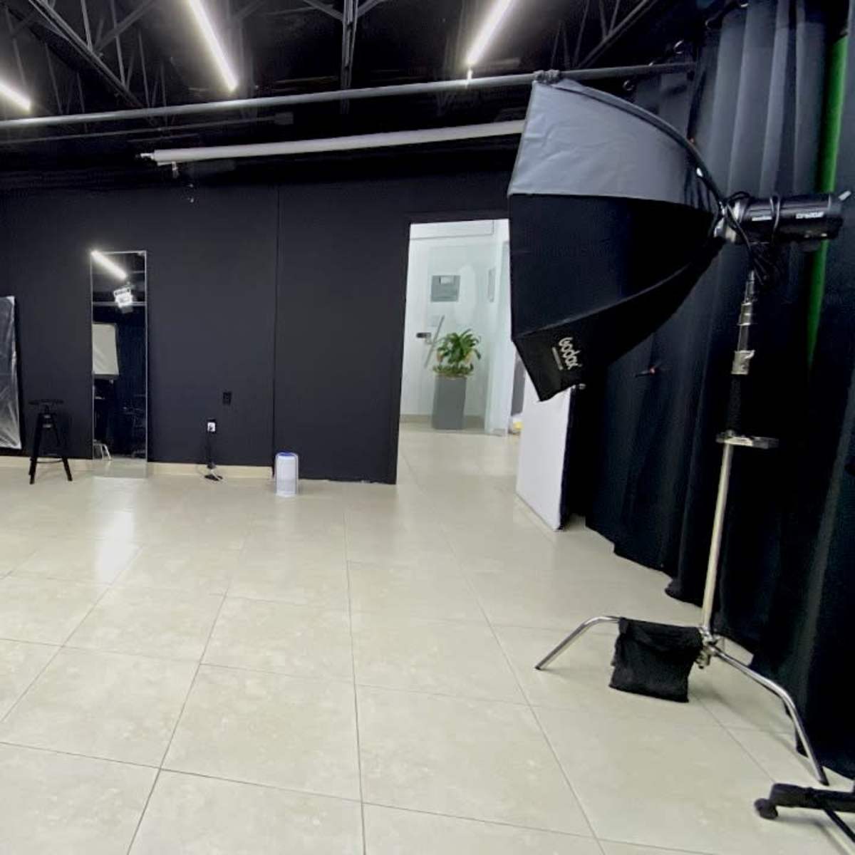 A photography studio with two light setups, a mirror, and a door leading to another room.